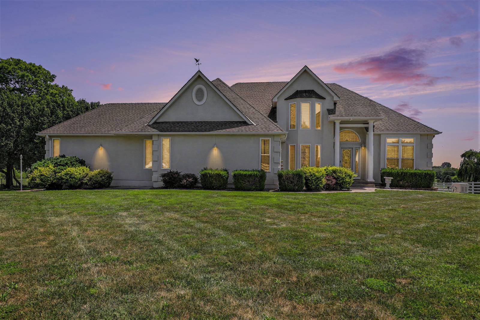 903 Doc Henry Road in Greenwood, Missouri, a two-story stucco home on 8.29 acres with three outbuildings and rolling pasture