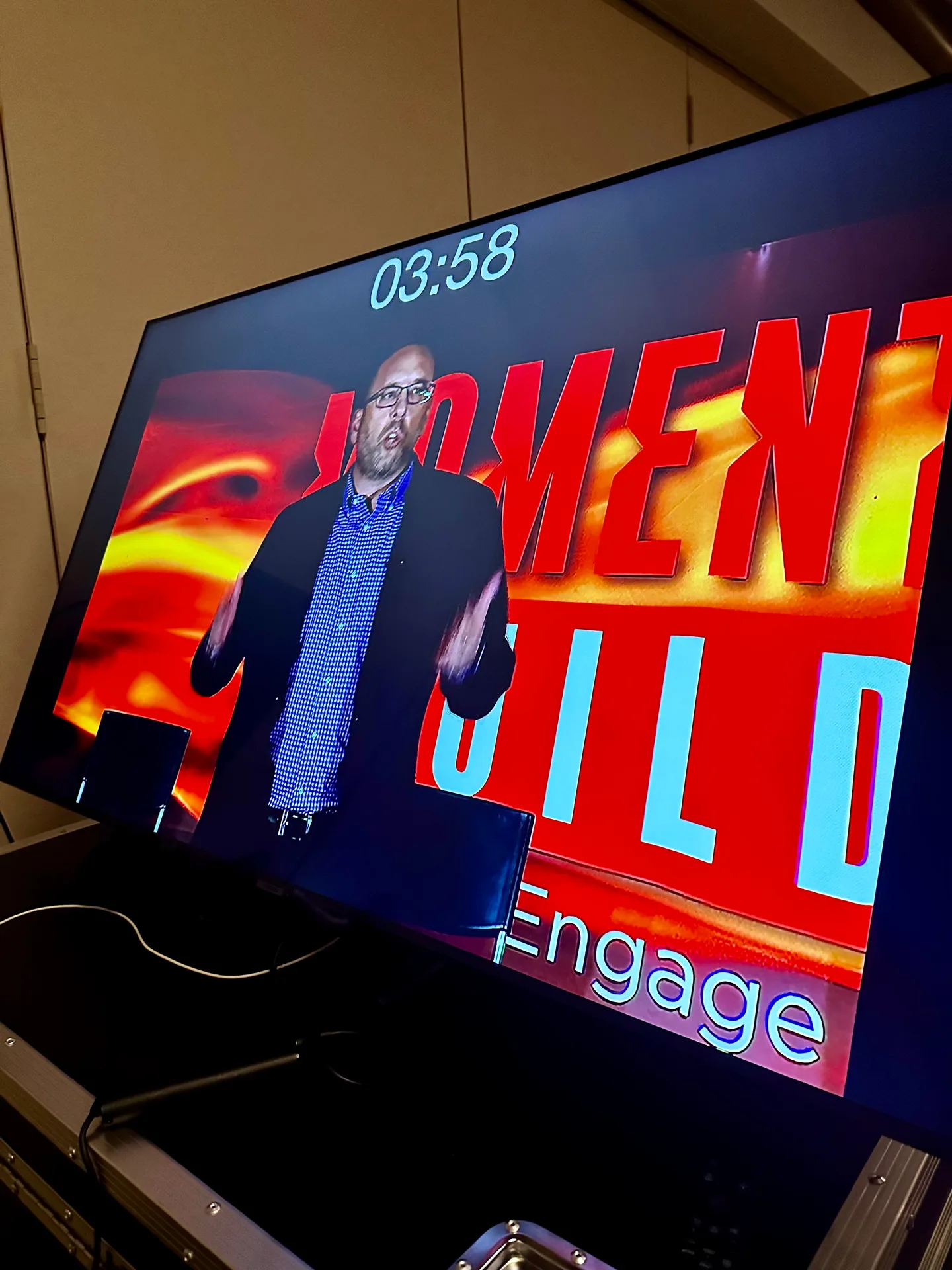 Craig Davis on the big screen during a keynote, MOMENT and BUILD graphics behind him