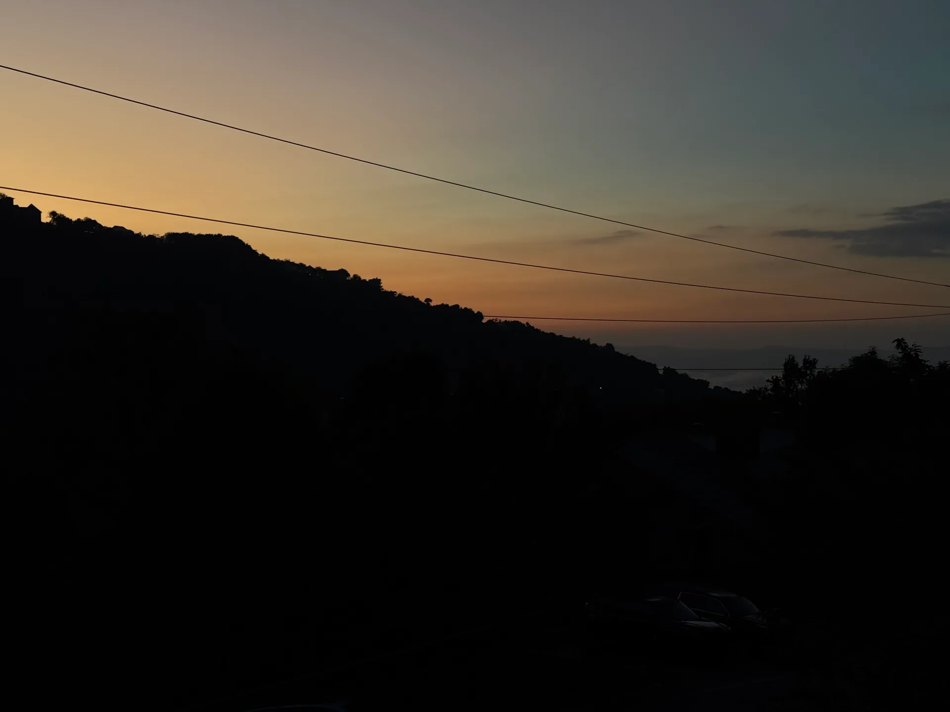 A tranquil sunset over the hillside with a soft gradient sky, seen from the cabin's back porch