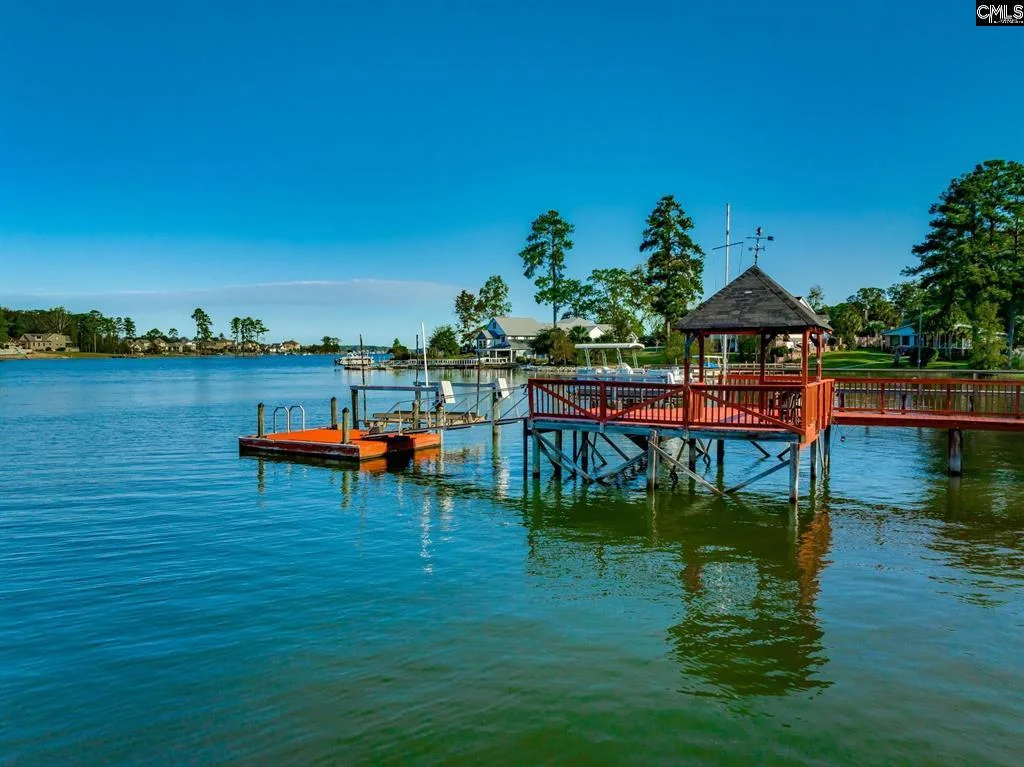 A wooden dock on a calm Lake Murray shoreline at golden hour, with a small boat tied at the end and pines along the far bank