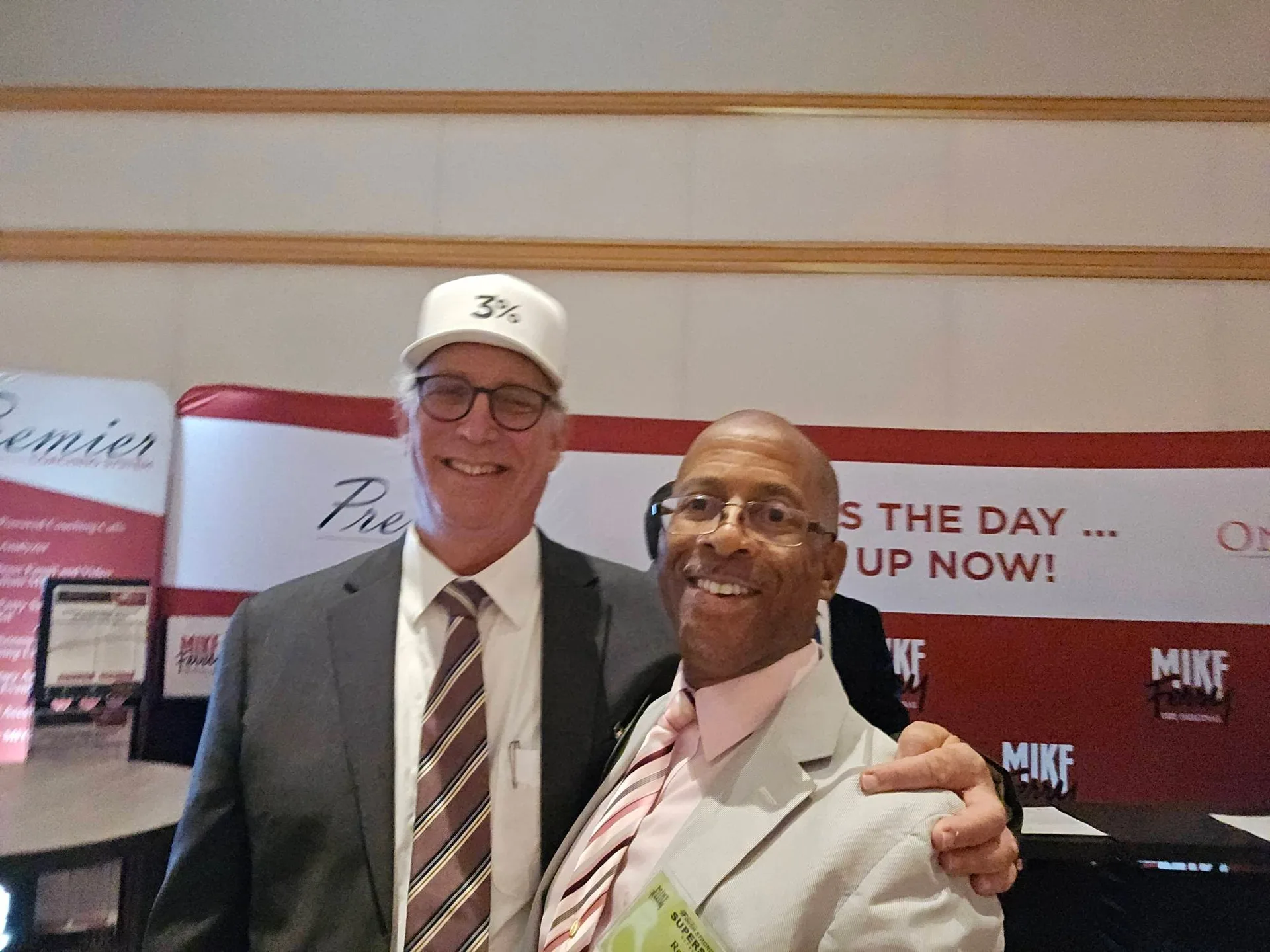 Robert Clarke poses with a fellow real estate agent in front of the Mike Ferry Premier branded backdrop banner at the Superstar Retreat venue