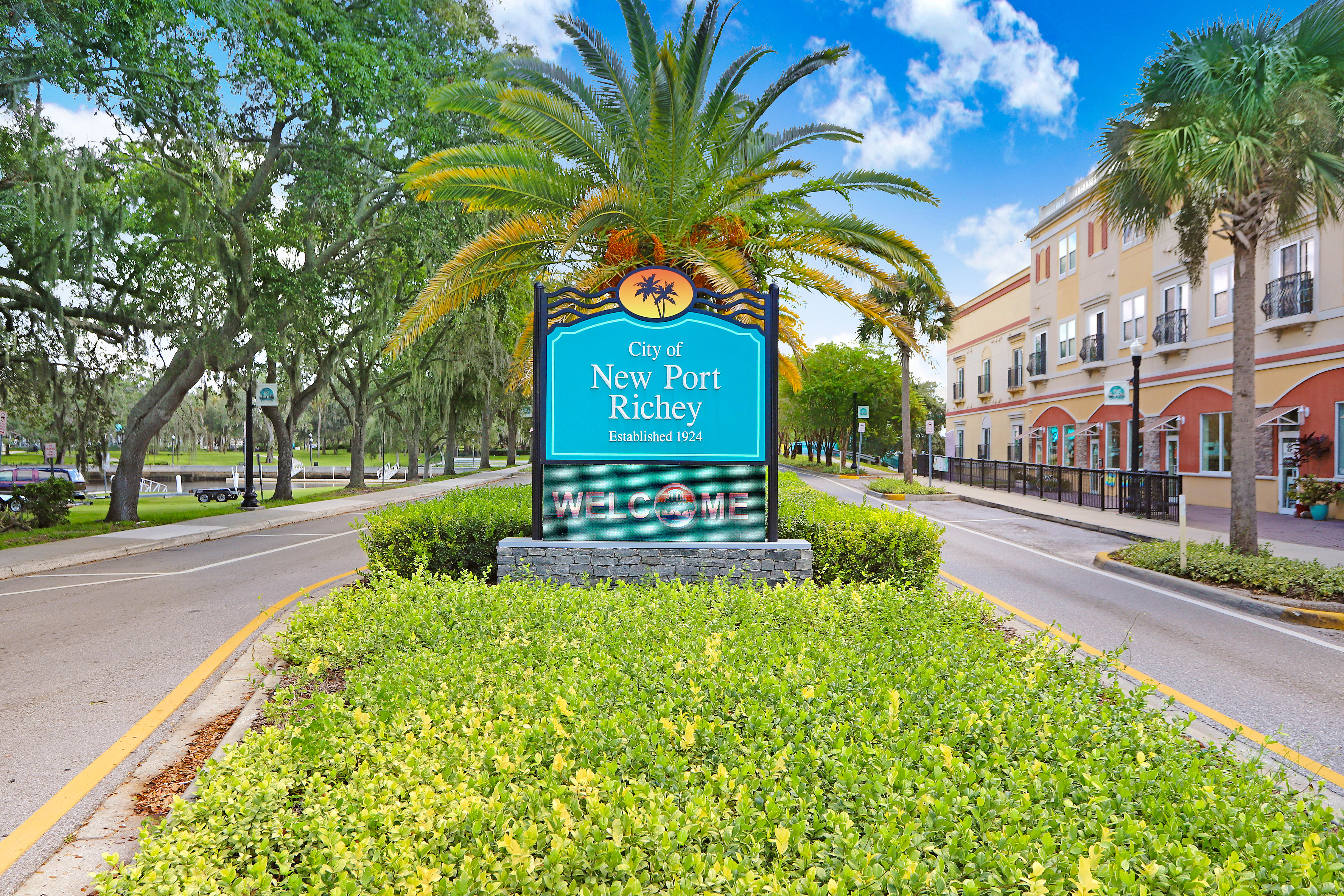 Downtown New Port Richey along Main Street, with historic buildings, storefronts, and palm trees under a bright blue sky