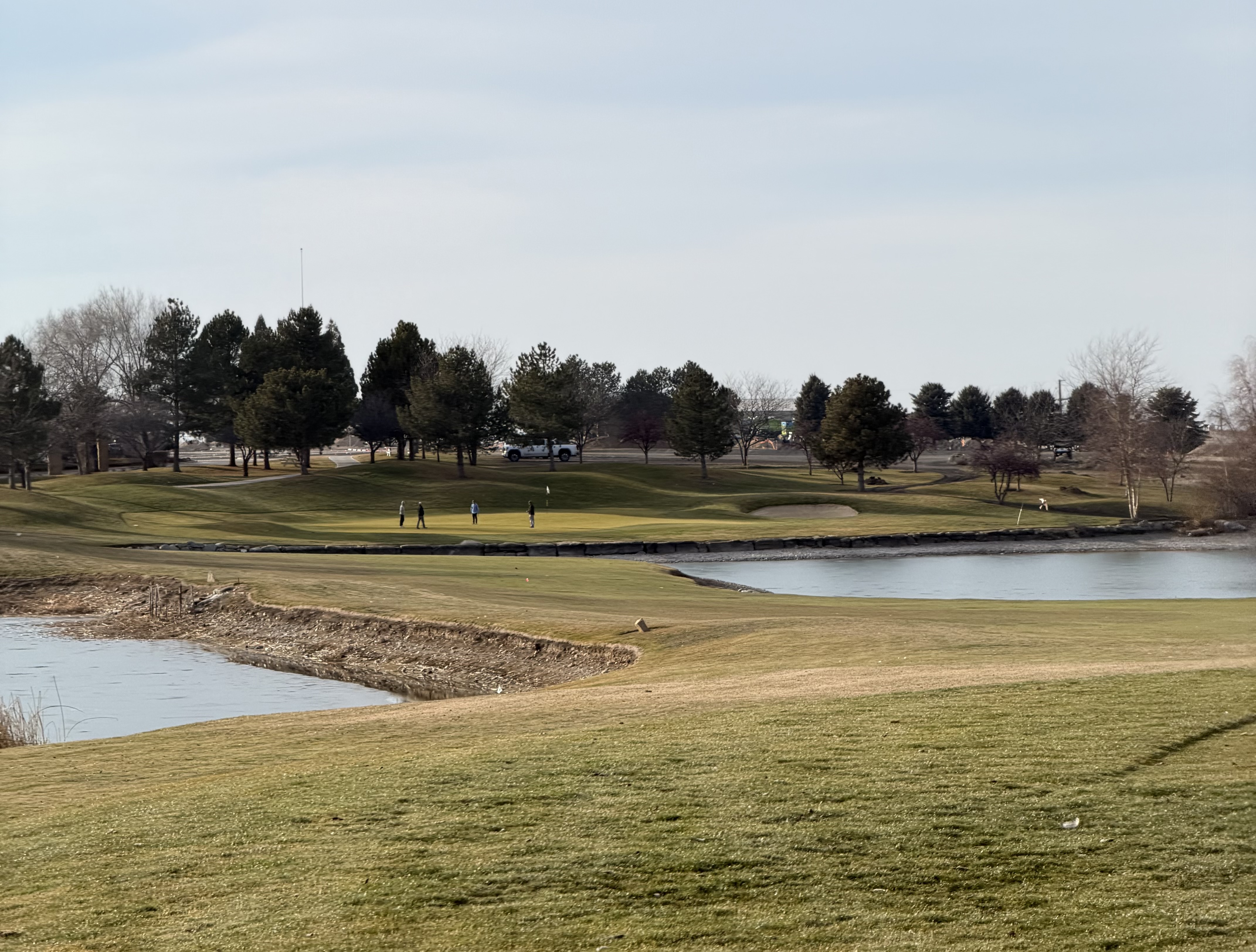 Falcon Crest Golf Club fairway stretching across rolling foothills with sagebrush, pine trees, and views of the Treasure Valley at golden hour