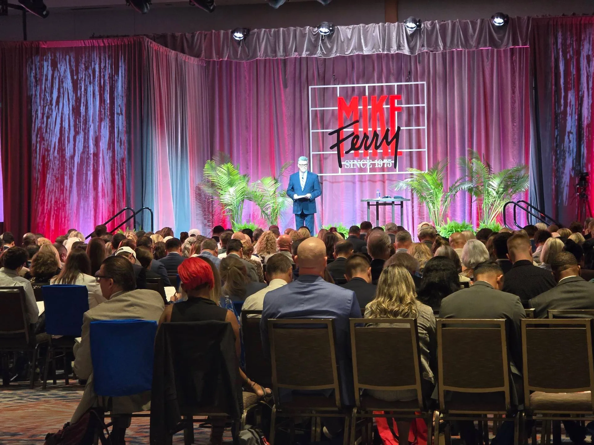 A speaker at the podium on stage during the Mike Ferry 2026 Superstar Retreat at The Diplomat Beach Resort in Hollywood, Florida, with the MIKE FERRY SINCE 1975 sign on the stage backdrop
