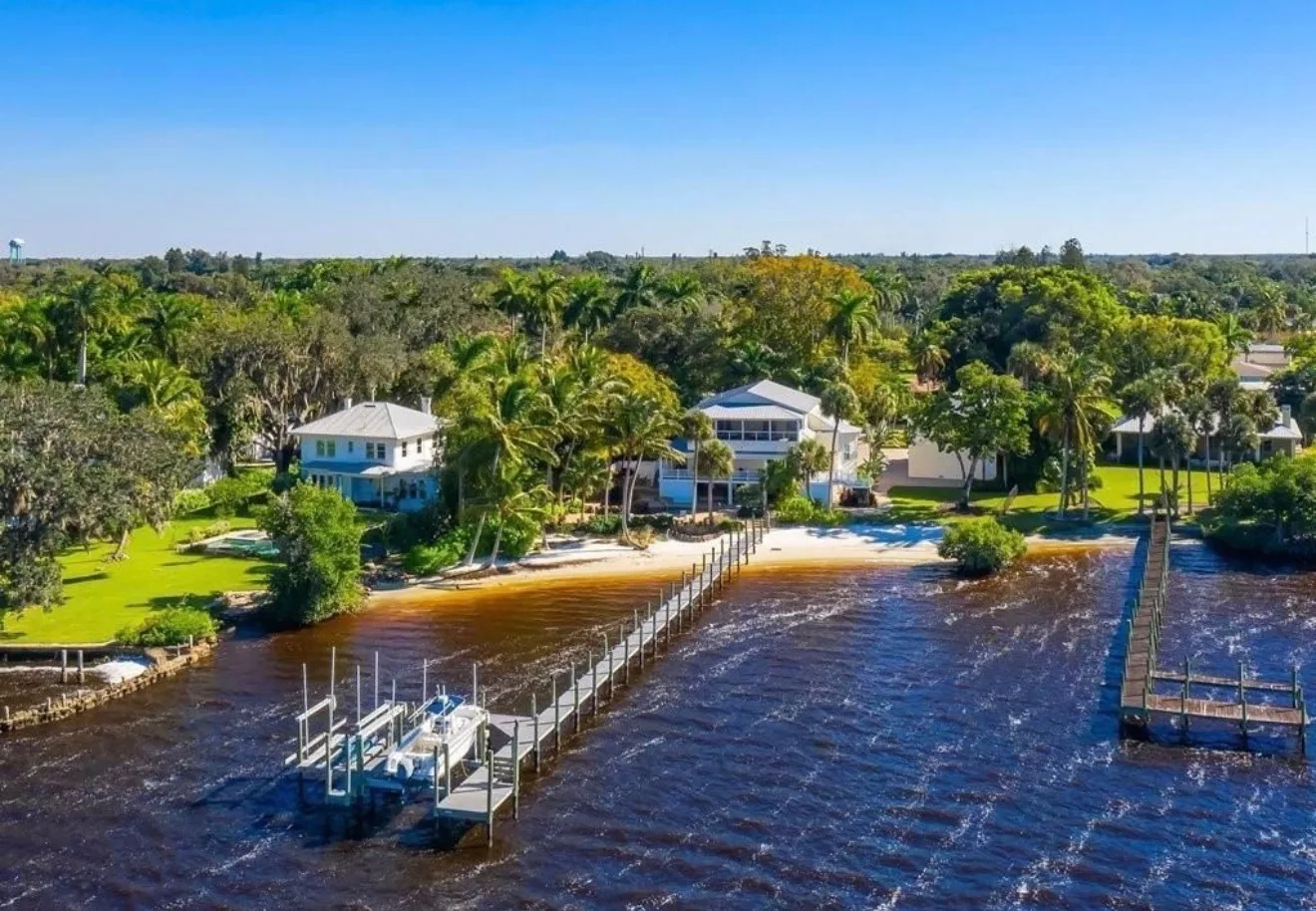 Covered porch with pool below and river and dock view beyond at the Fort Myers estate