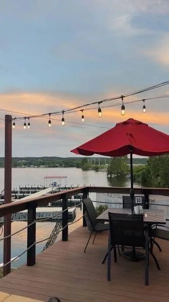 Lakefront patio seating with a red umbrella and string lights overlooking the boat docks at Iron Horse Landing on Lake Hudson
