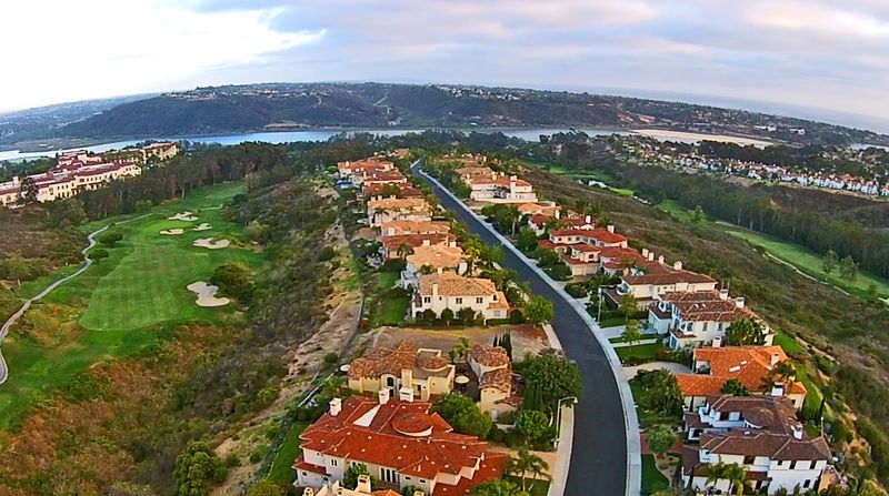 An upscale gated golf community in Carlsbad at dusk, fairways and a lake reflecting warm clubhouse lights