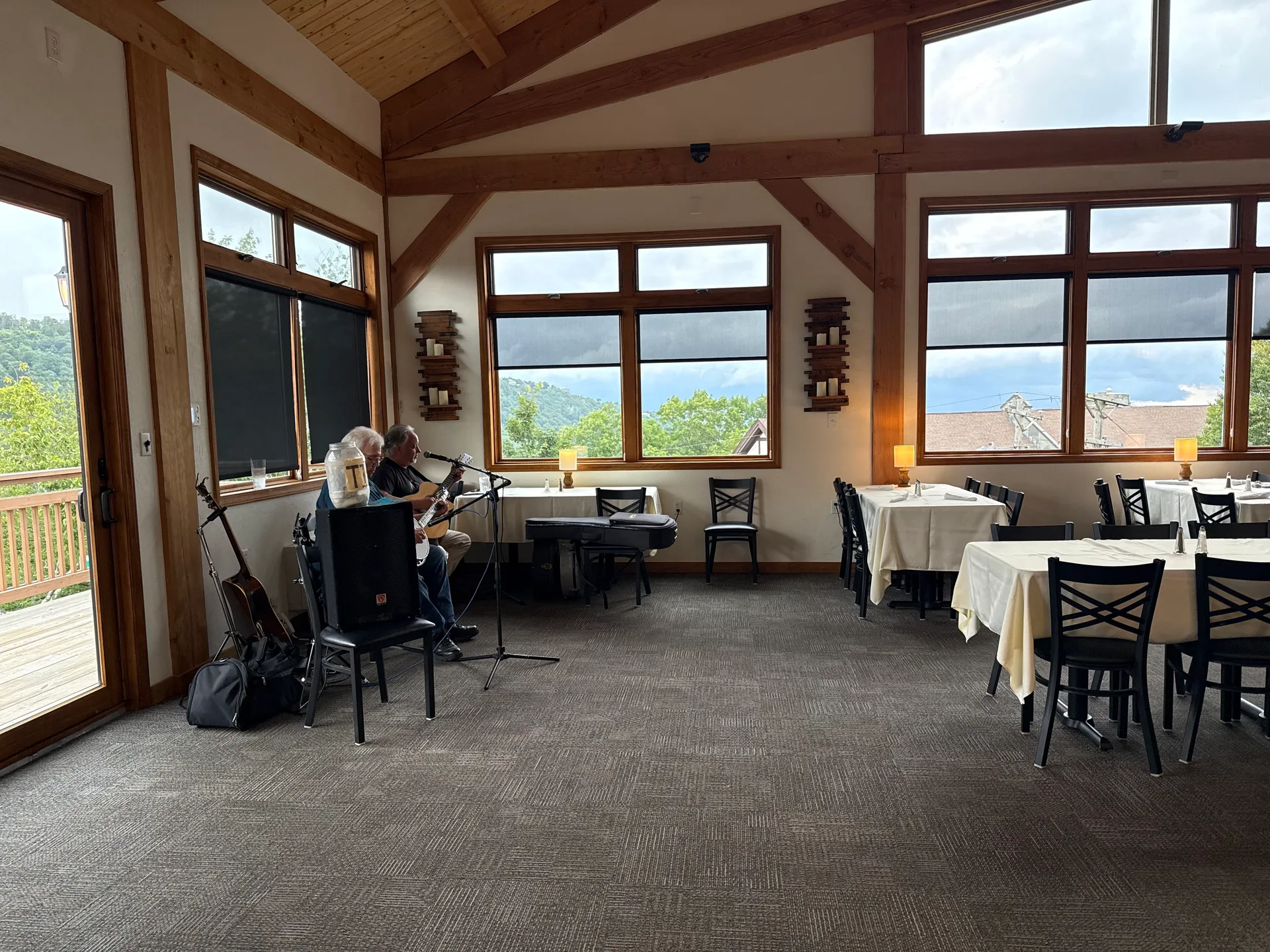 The spacious dining room at the Steakhouse at Alpen Inn in Beech Mountain, with wooden beams overhead, large windows, and tables set with white tablecloths