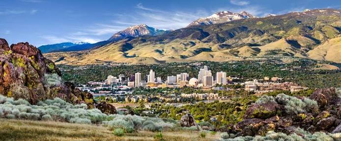 Downtown Reno skyline with business district at golden hour, mountain backdrop.