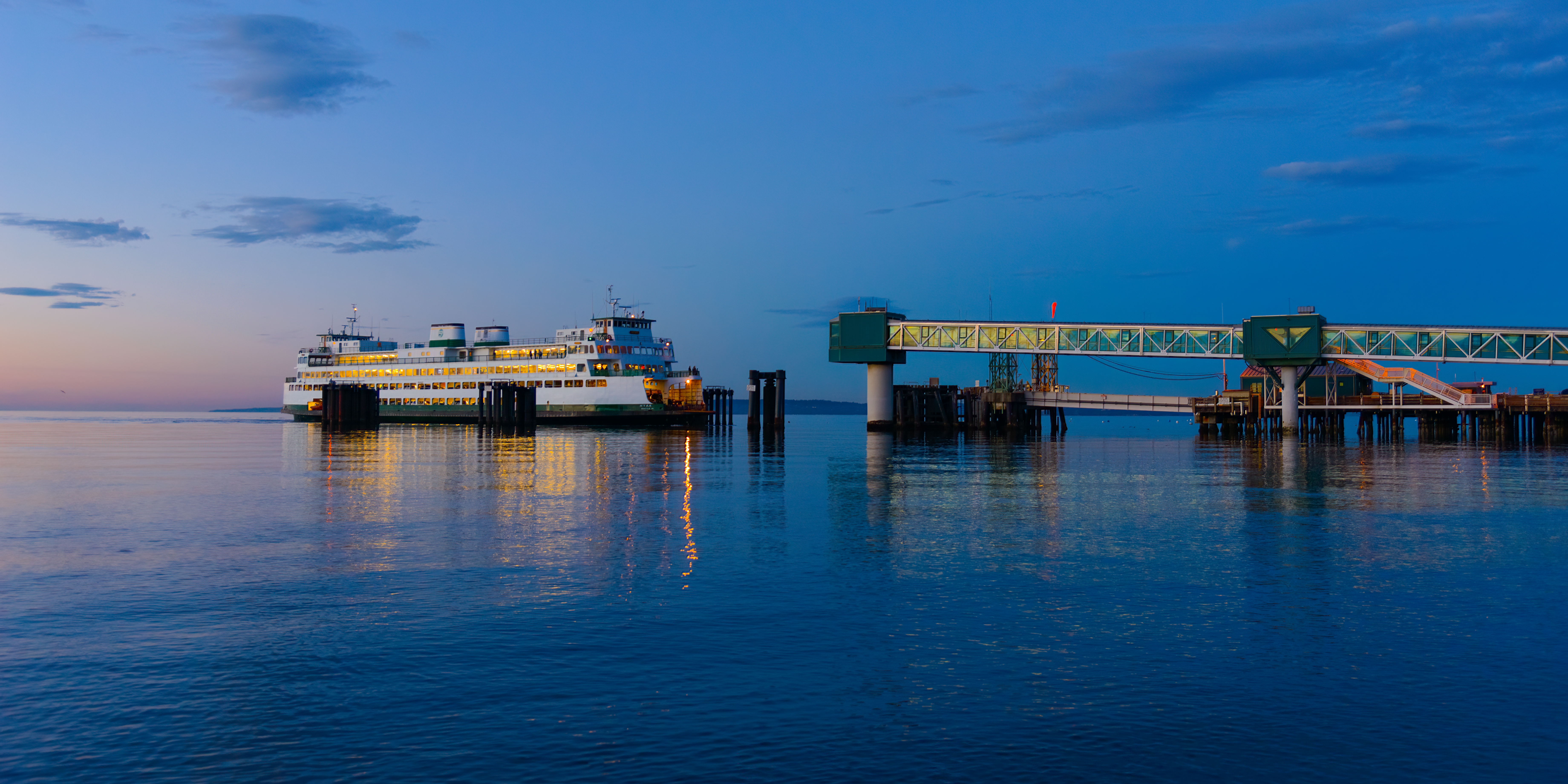 A Washington State Ferry at the Edmonds ferry terminal at twilight, lights glowing on the hull as it rides the waters of Puget Sound