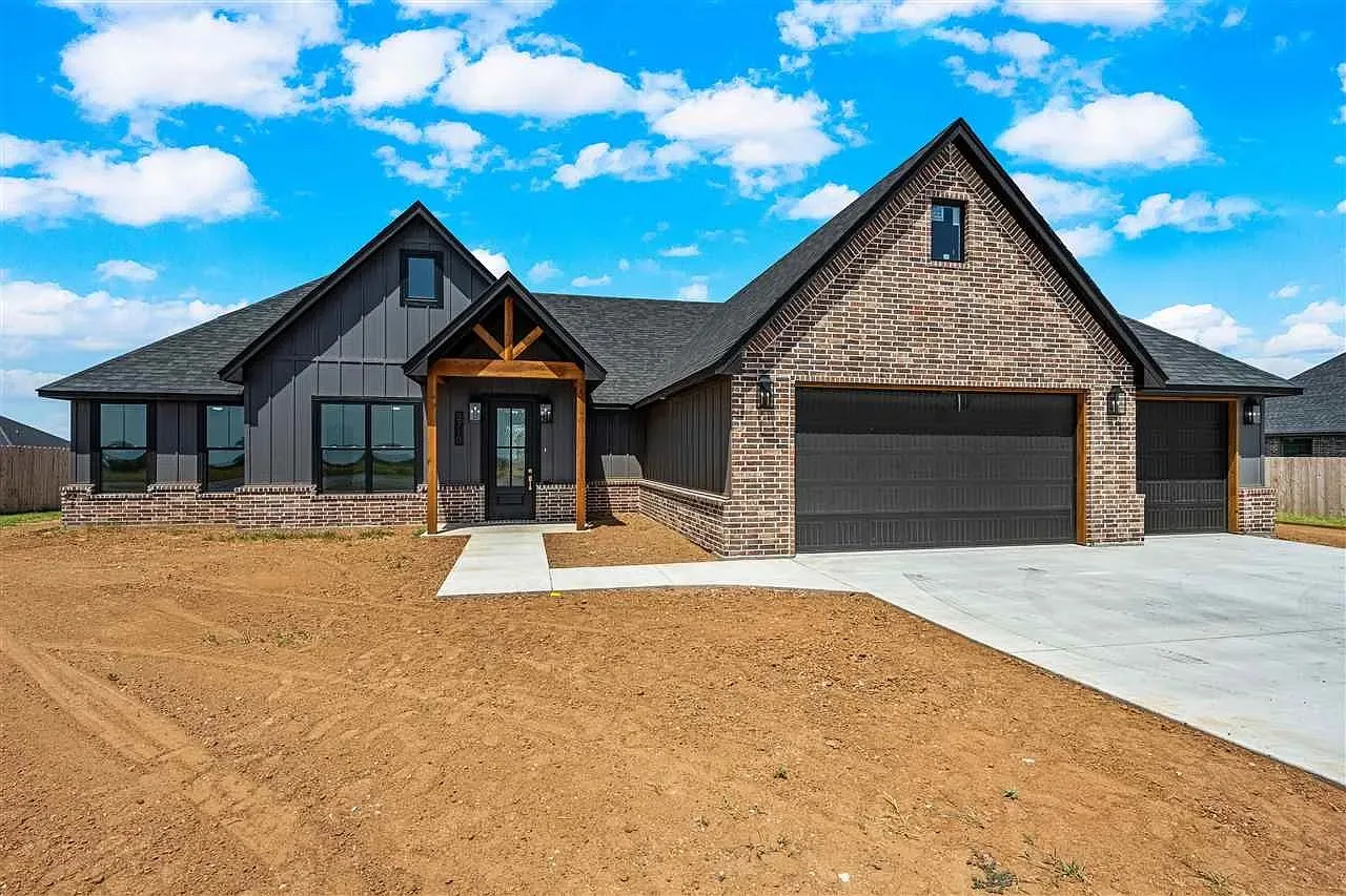Newly built modern farmhouse style home in Elgin, Oklahoma with dark brick and board-and-batten siding