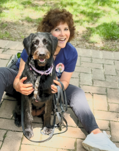 Dog trainer Lisa Desatnik sitting outdoors with a dog.