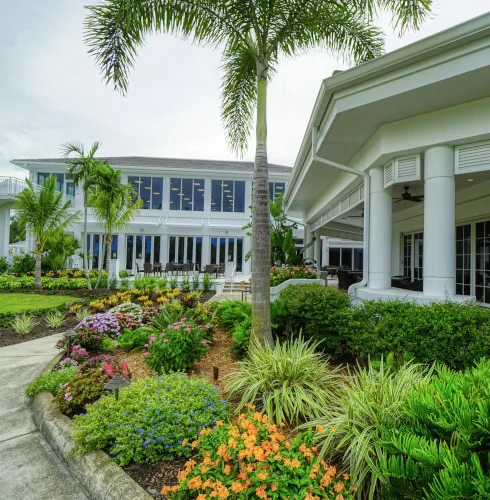 Community pool area with lounge chairs, yellow umbrellas and palm trees in the Gateway community of Fort Myers