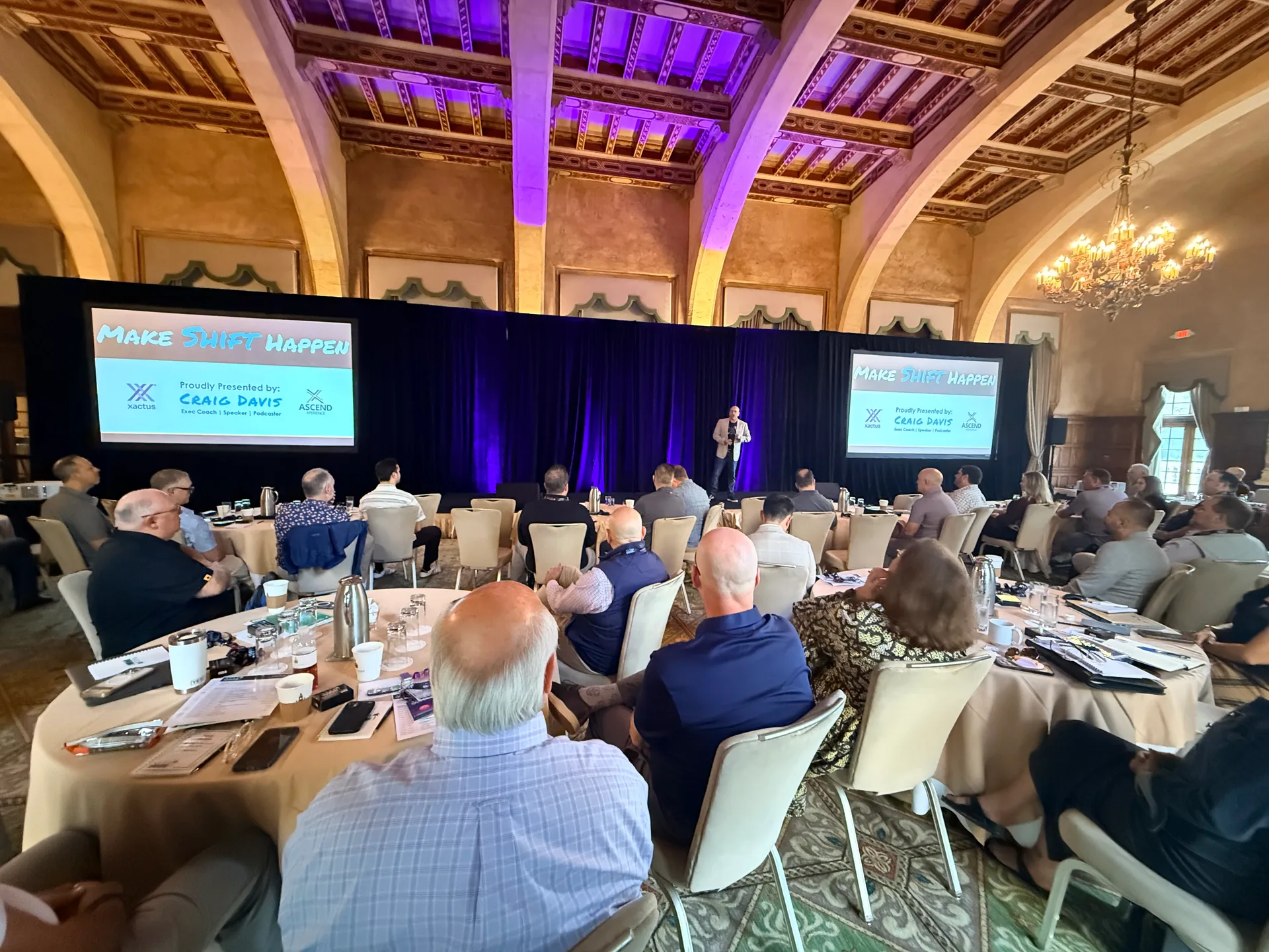 Craig Davis on stage with the Make Shift Happen slide at the Xactus Sales Kickoff in Miami