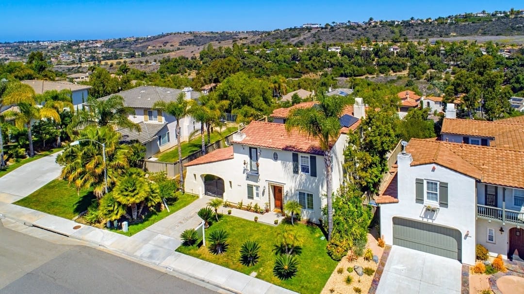 A planned hillside community in Carlsbad at dusk with warm-stone homes terraced up a gentle slope