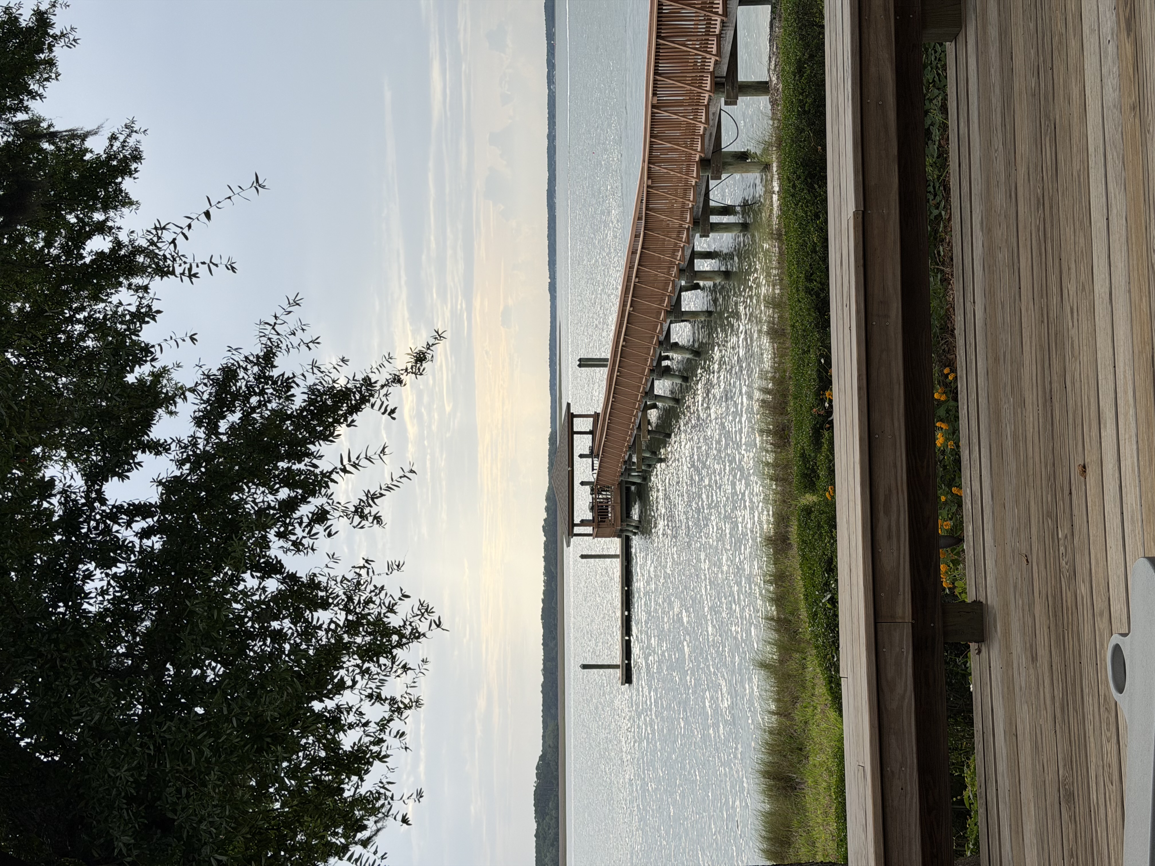 Bluffton Lowcountry wooden pier with a covered gazebo, a bench in the foreground, and marsh grass in soft muted dawn light