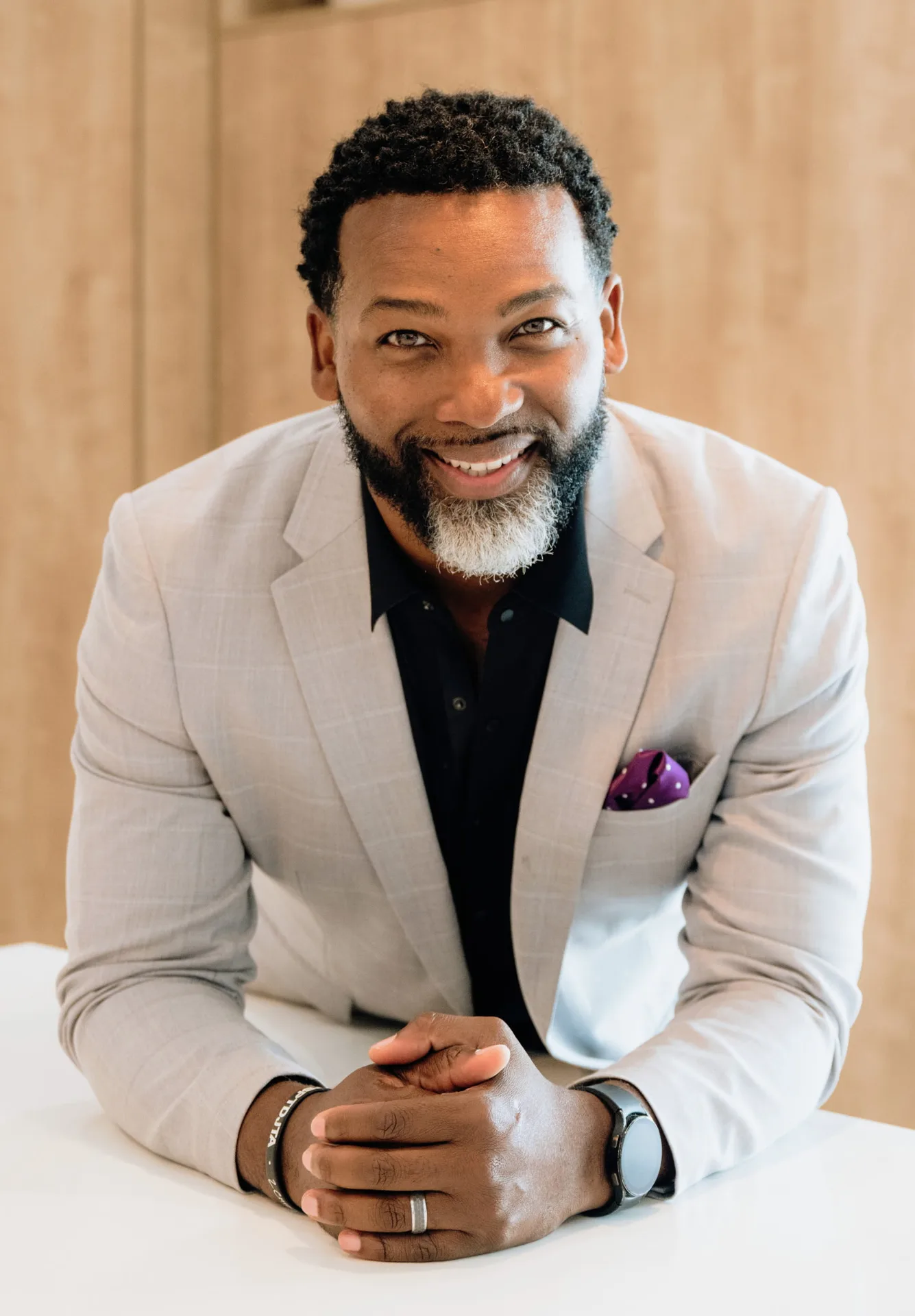 Mike Collier, real estate agent with eXp Realty in Southwest Orlando, smiling in a light grey blazer with a black collared shirt and purple polka-dot pocket square