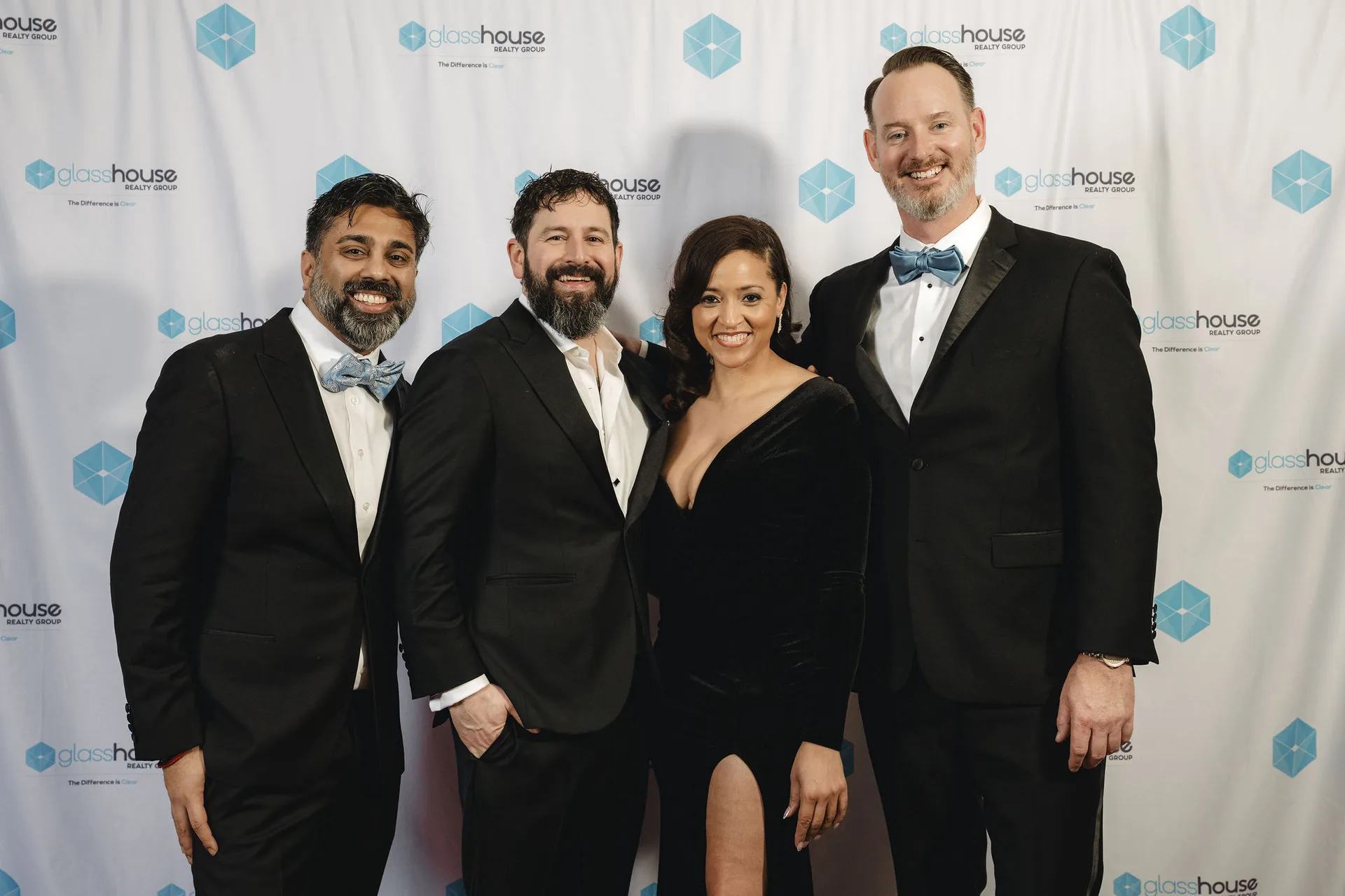 Glasshouse Realty Group team group photo of four people in front of a branded backdrop