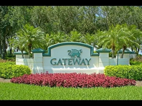 Gateway entrance sign with stone monument, tropical landscaping, and palm trees at the Fort Myers master-planned community