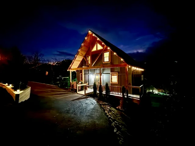The Heart of Beech Retreat cabin exterior at night, with warm string lights glowing along the eaves