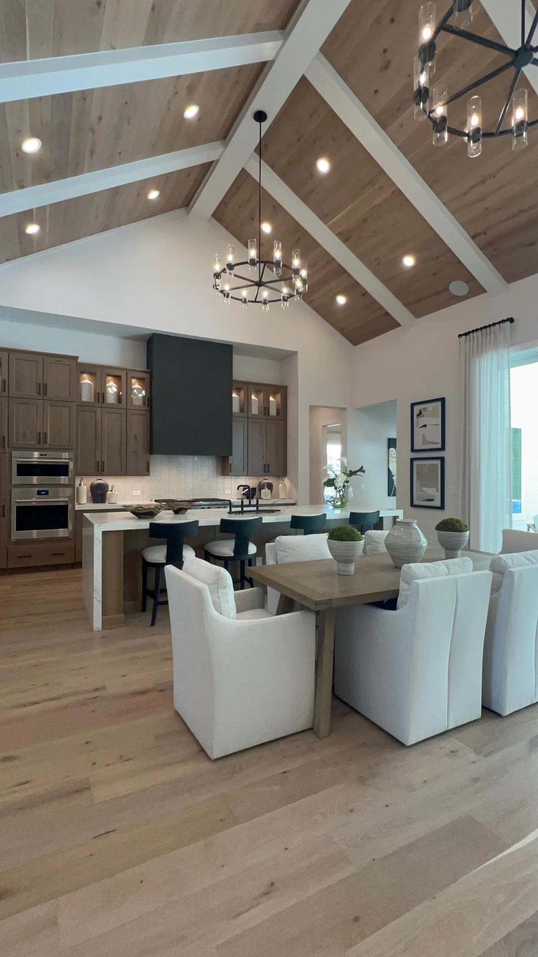 Mollie's kitchen and dining area in Ponte Vedra with a large island, dark cabinetry, and wood beams