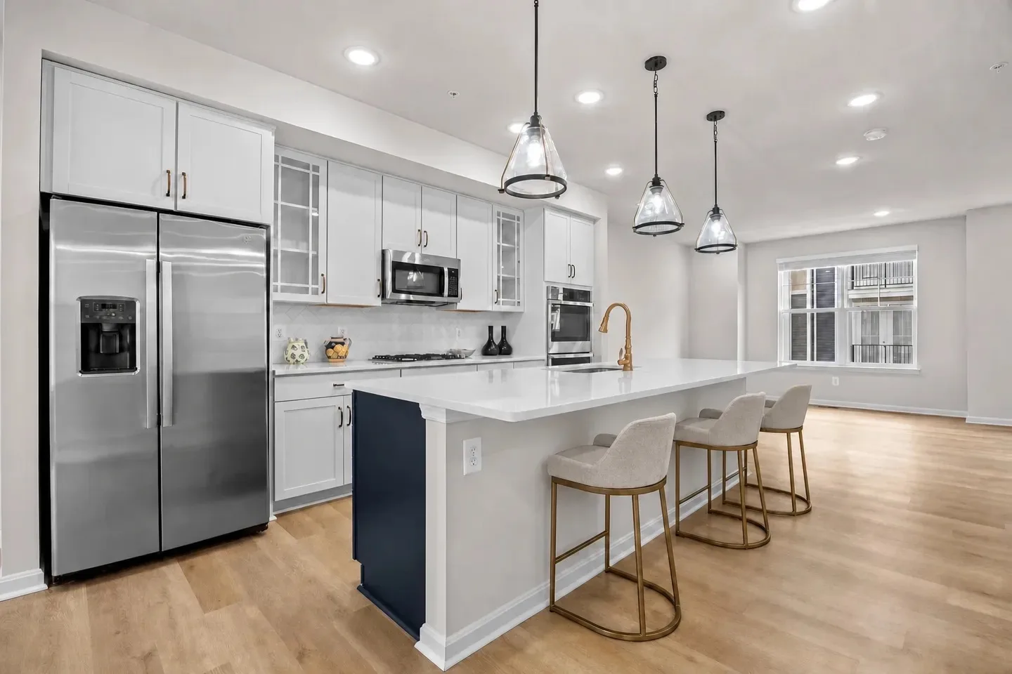 Kitchen island with quartz countertop, three counter stools, and bronze faucet and hardware