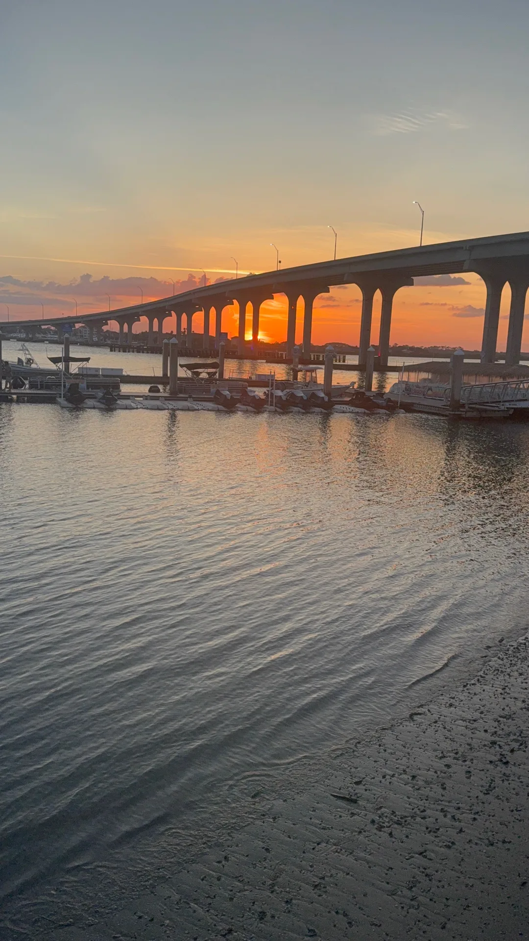 Boats moored at wooden piers beneath a bridge at sunset on the water near Ponte Vedra, Florida