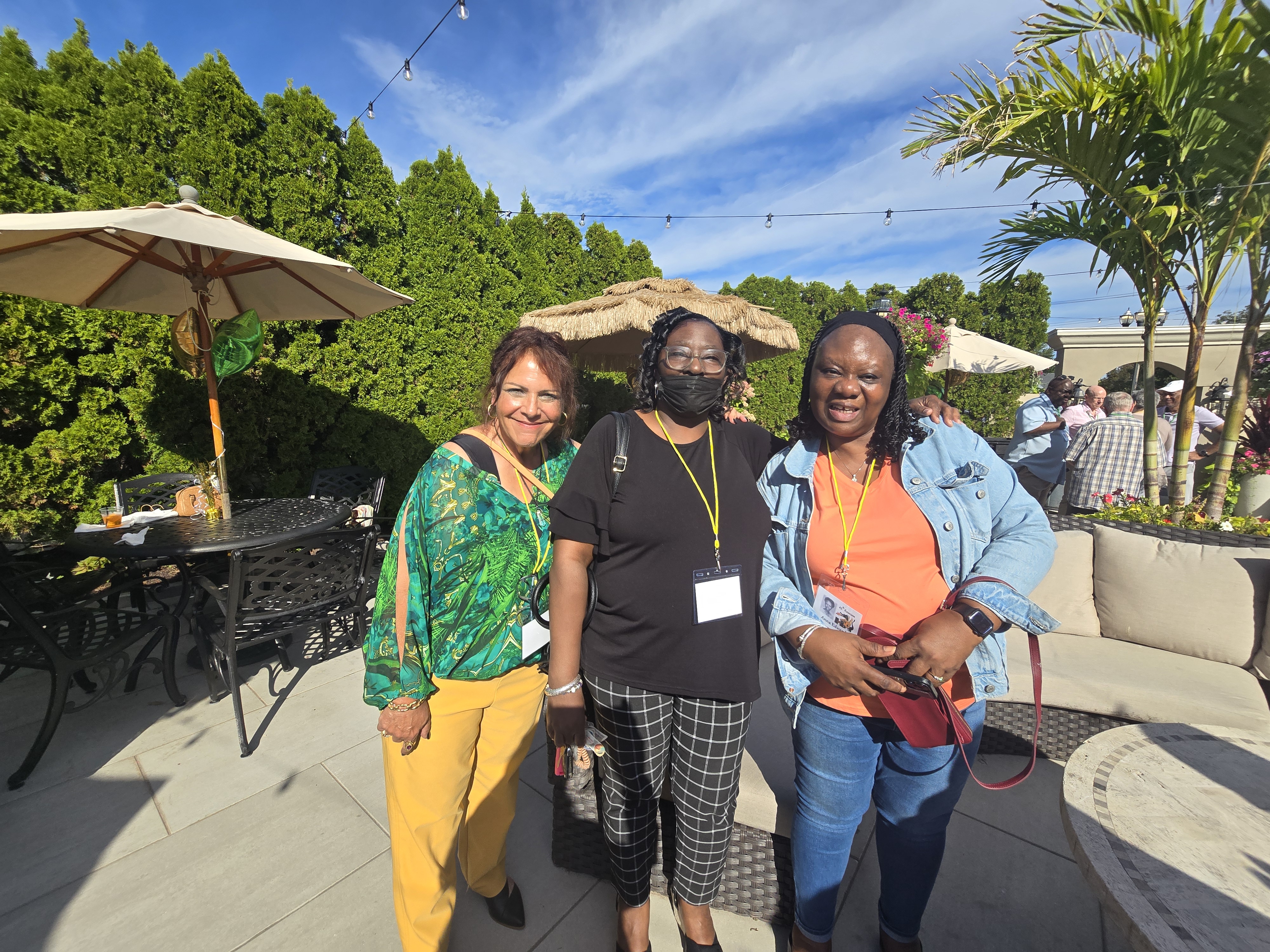 Three women wearing reunion name tags smiling and catching up on the sunny patio at the Hamden High Class of 1981 45th reunion.