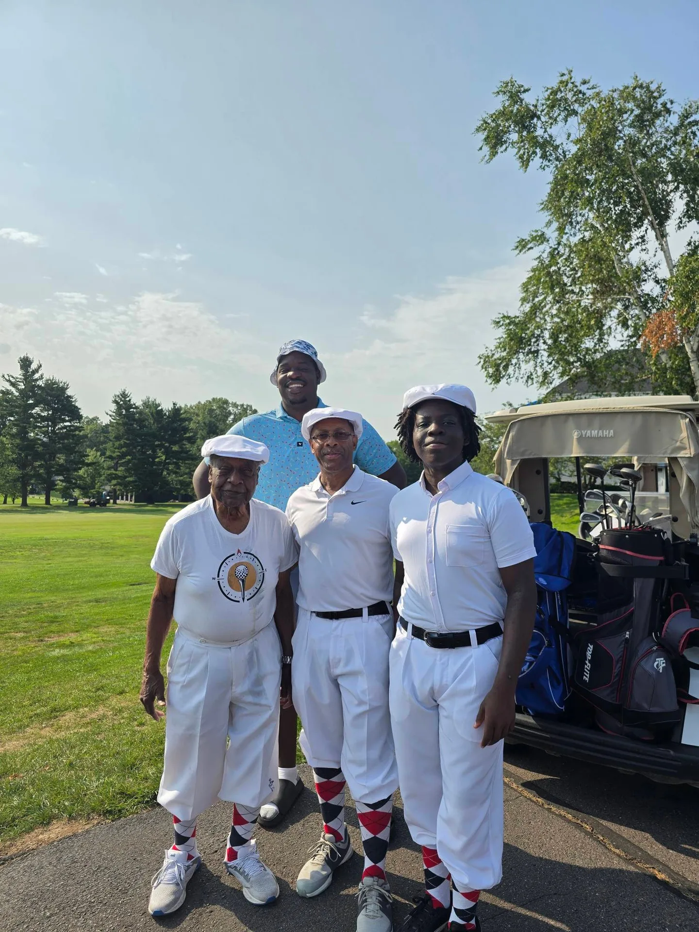 A foursome in matching white knickerbocker-style outfits ready to hit the links at the Calcagni Golf Classic