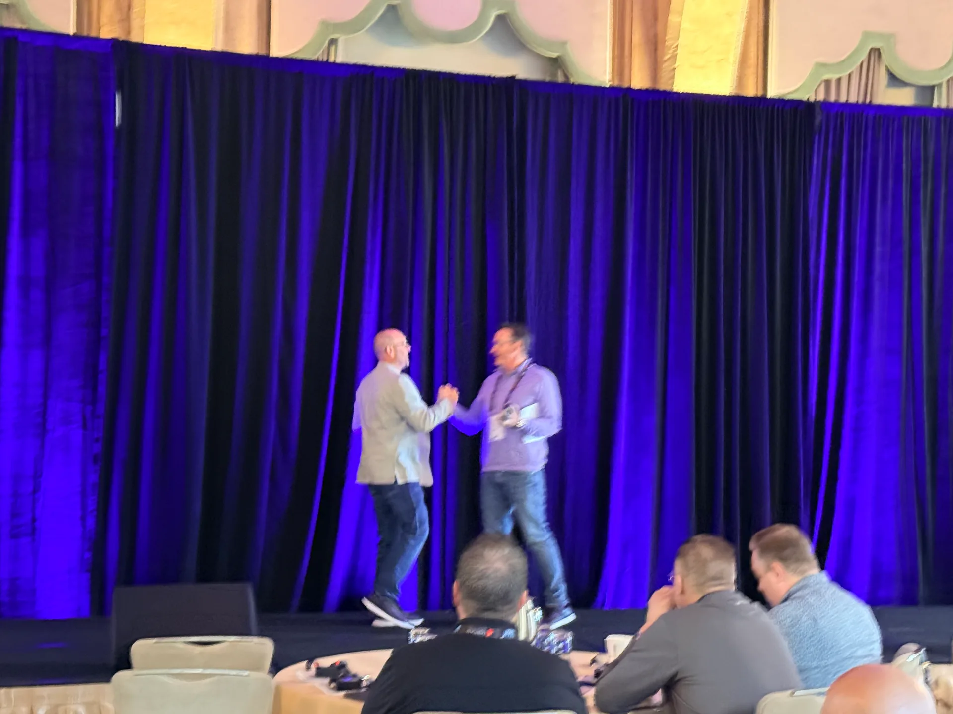 A handshake on stage at the Xactus Sales Kickoff in Miami