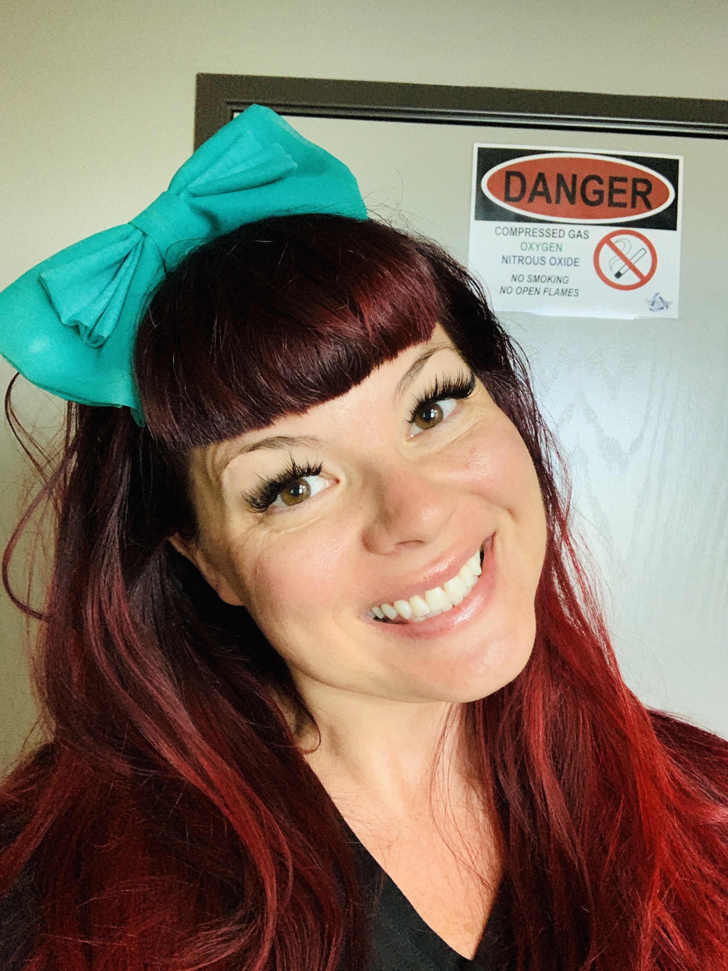 Samantha Medeiros standing in front of a DANGER compressed gas sign demonstrating safety awareness and compliance protocols