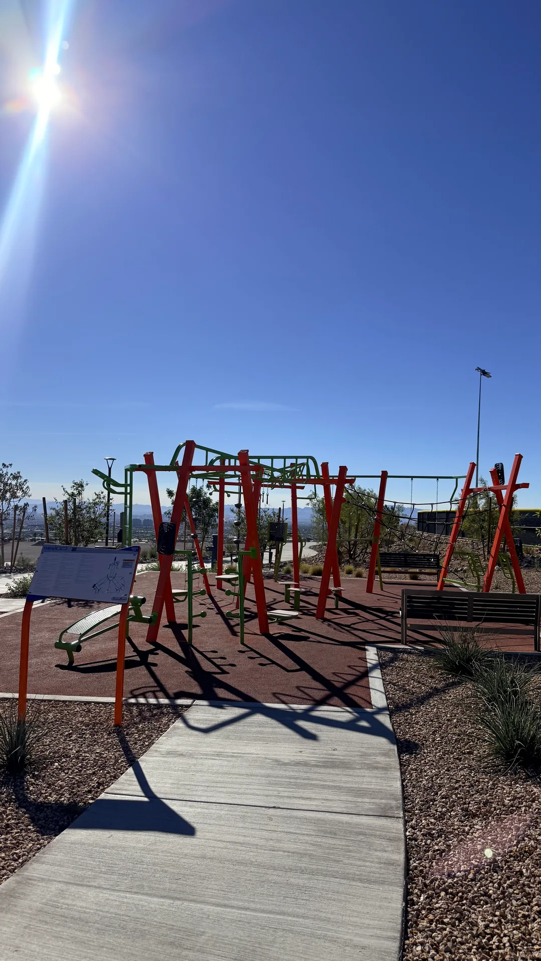 Orange and green climbing playground structure on rubber surfacing in a Summerlin community park