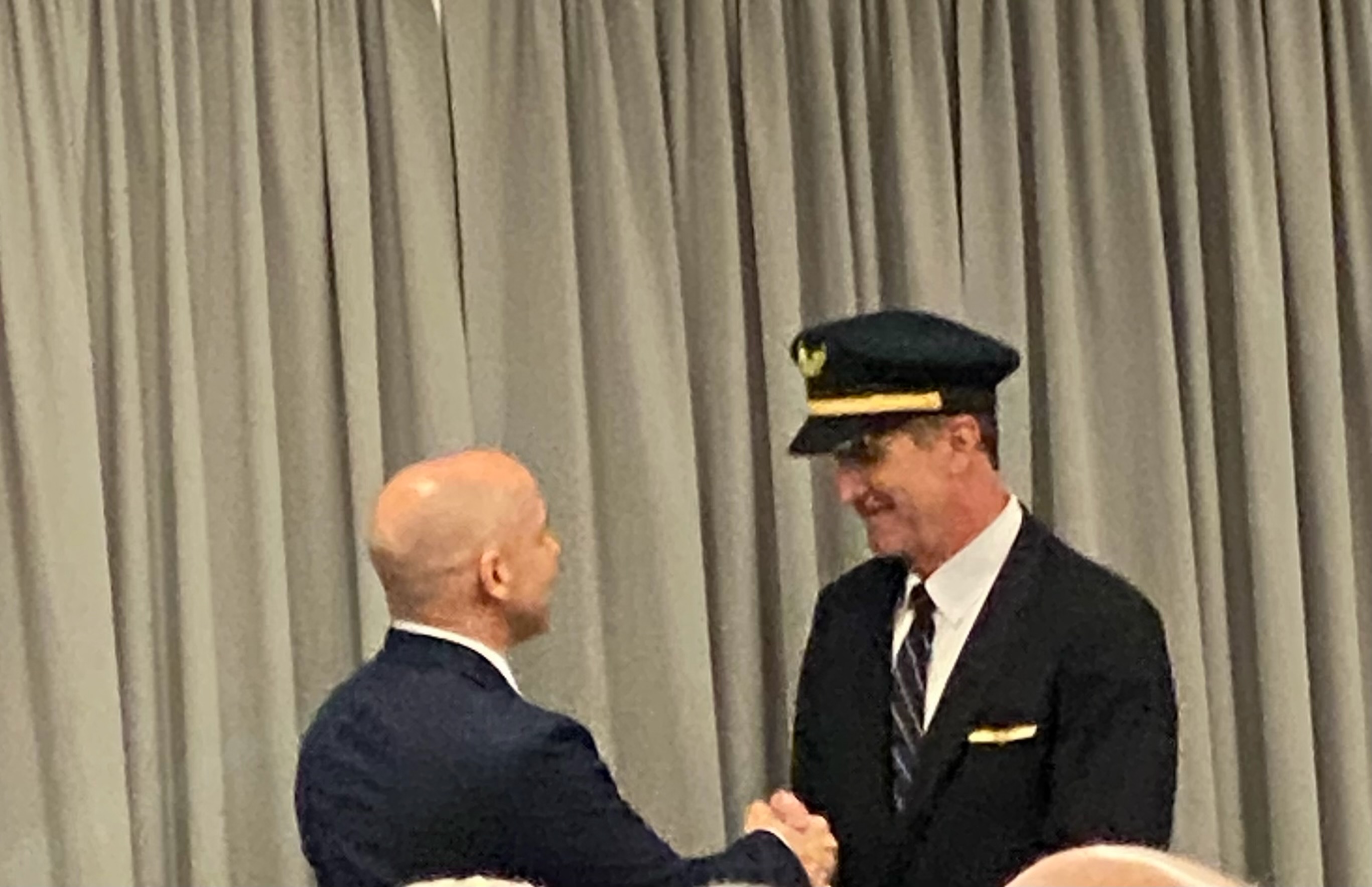 Pilot in uniform shaking hands at a formal ceremony, a dignified and personal moment
