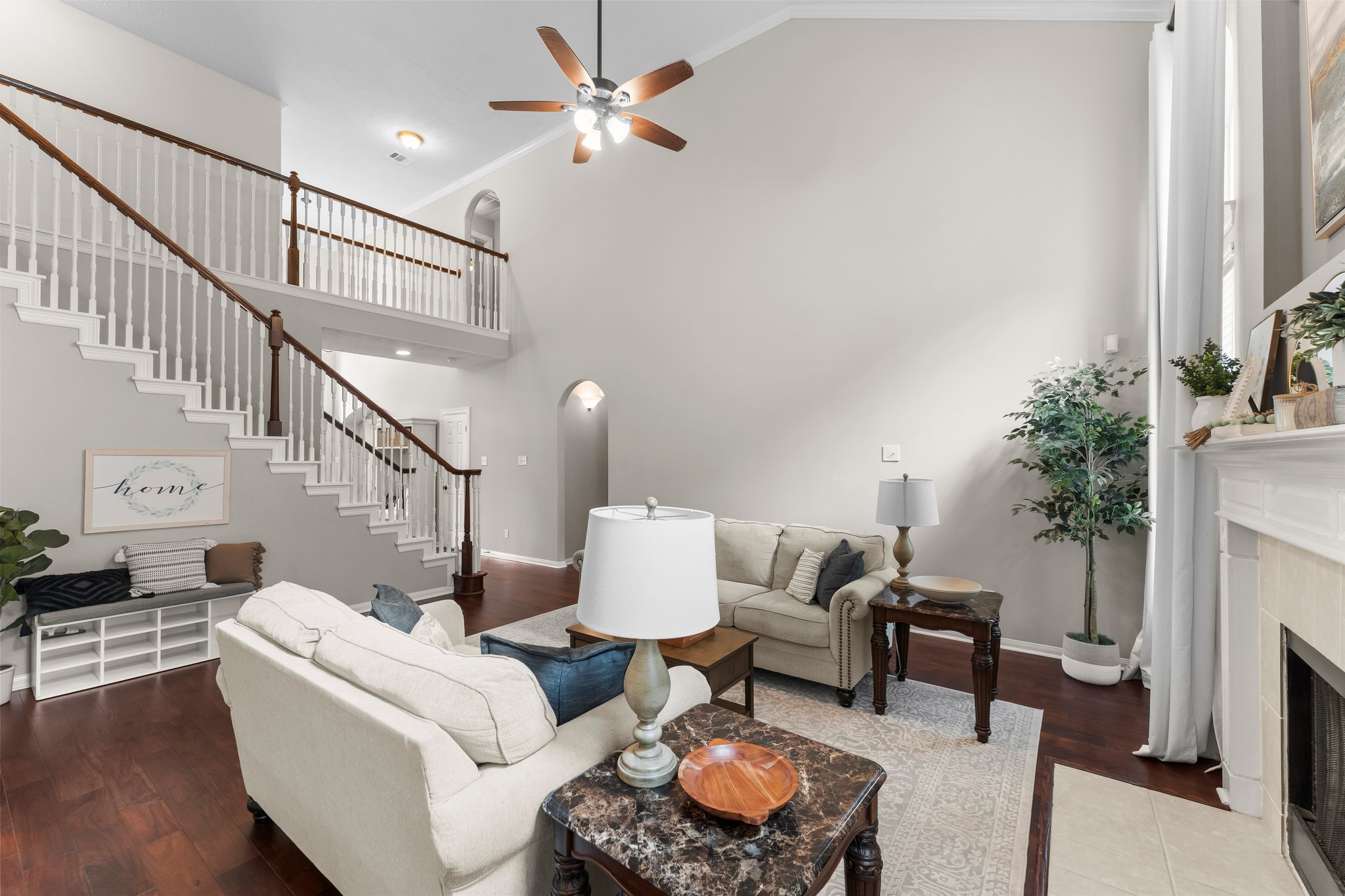 A living room with a vaulted ceiling and staircase, prepared at its best for buyers