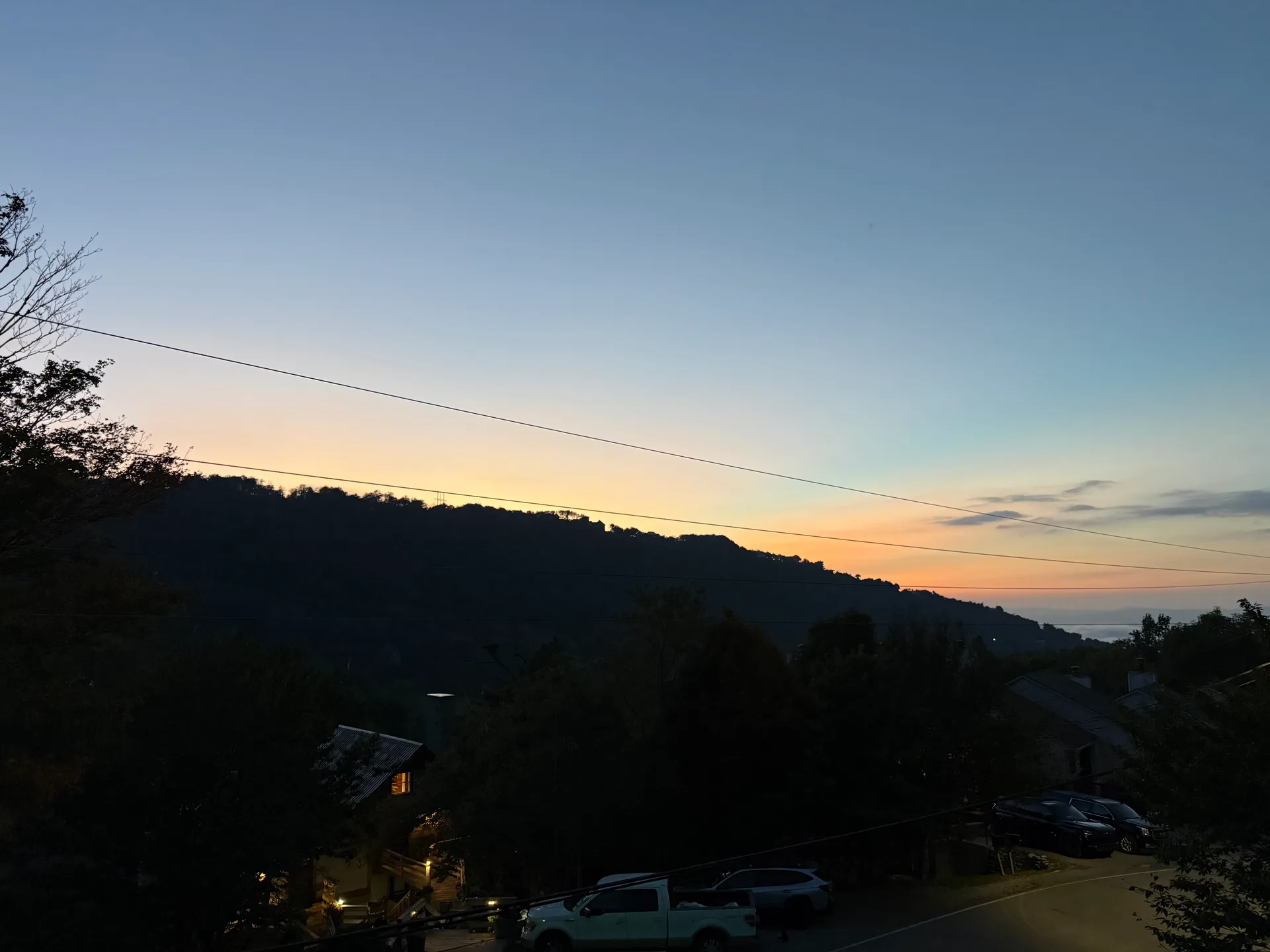A glowing orange and yellow horizon over the mountain landscape, seen from the cabin's back porch