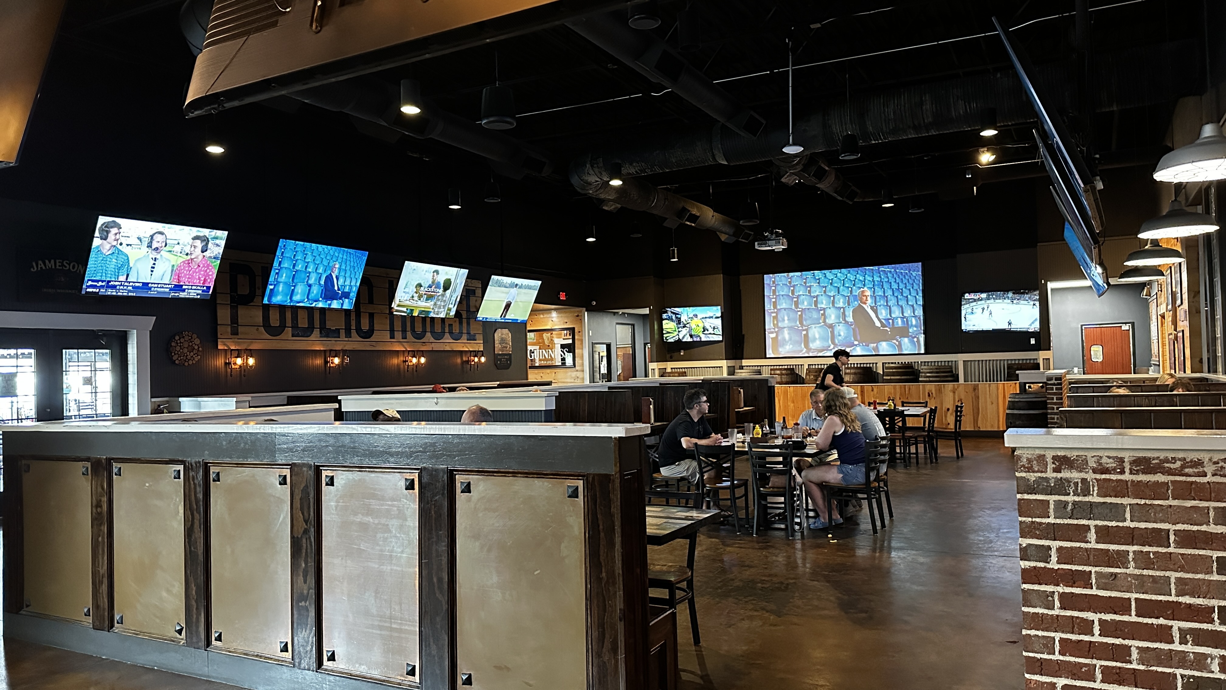 Dining room at Jack's Public House in Braselton Georgia with exposed ductwork dark wood finishes and numerous TVs showing sports