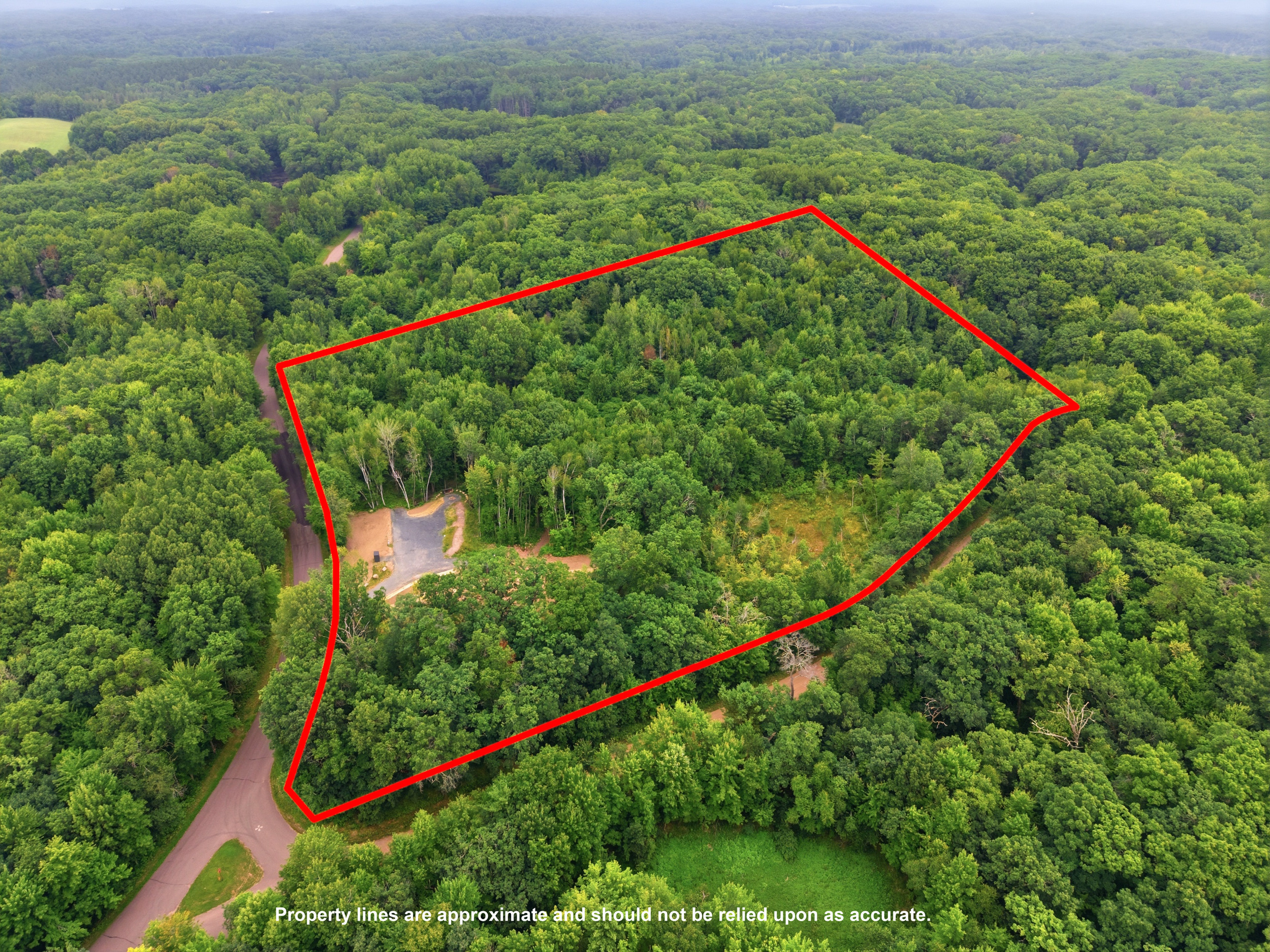 Two-story white house and outbuildings on wooded property at 25307 144th Street in New Auburn, Wisconsin