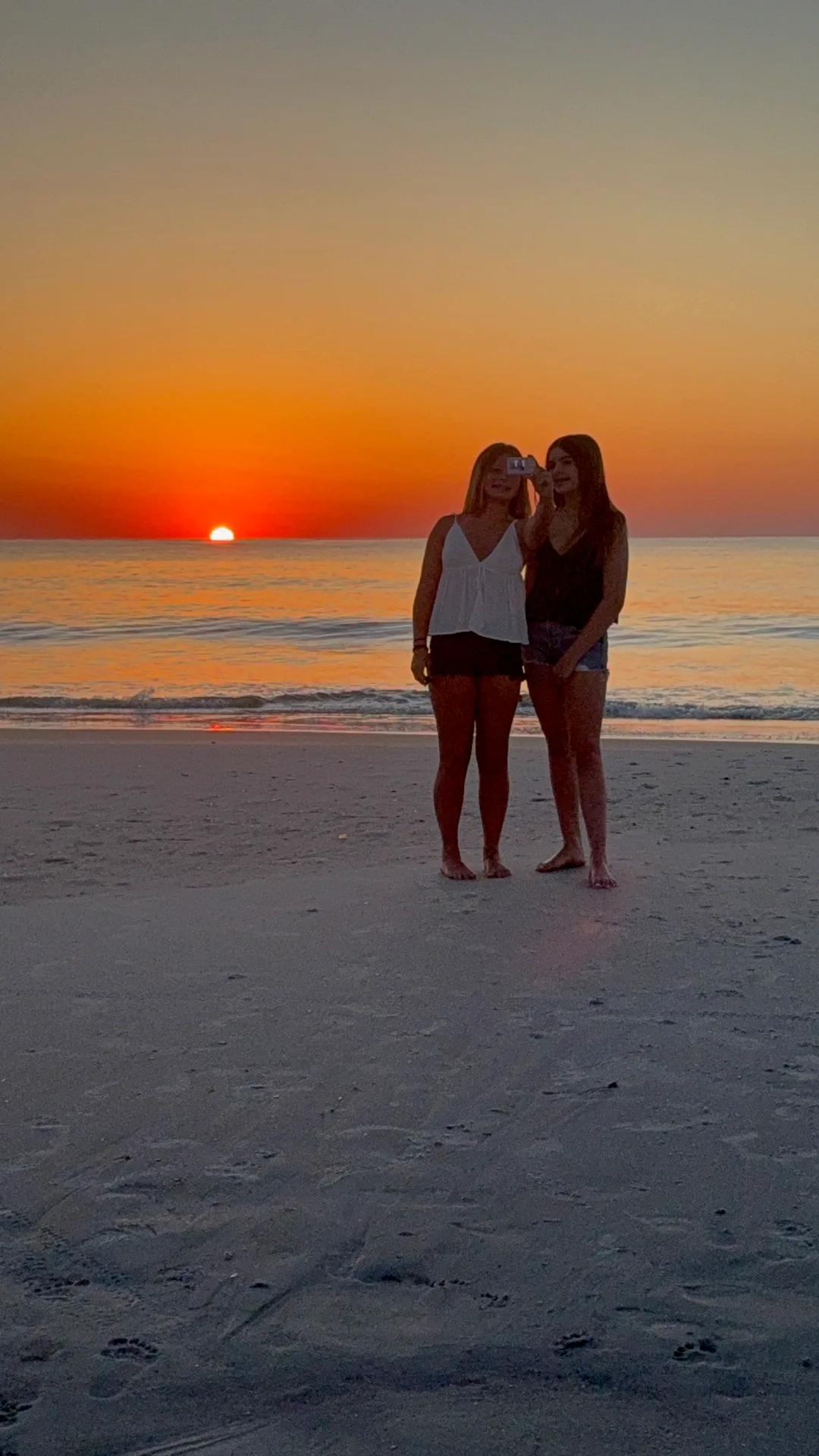 Two friends taking a selfie on the sand at sunset over the ocean near Ponte Vedra