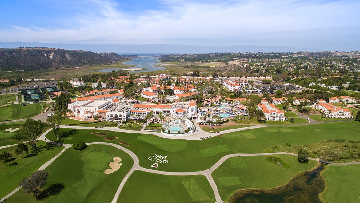 A classic luxury golf-course neighborhood in Carlsbad at dusk with eucalyptus silhouettes and warm glowing homes