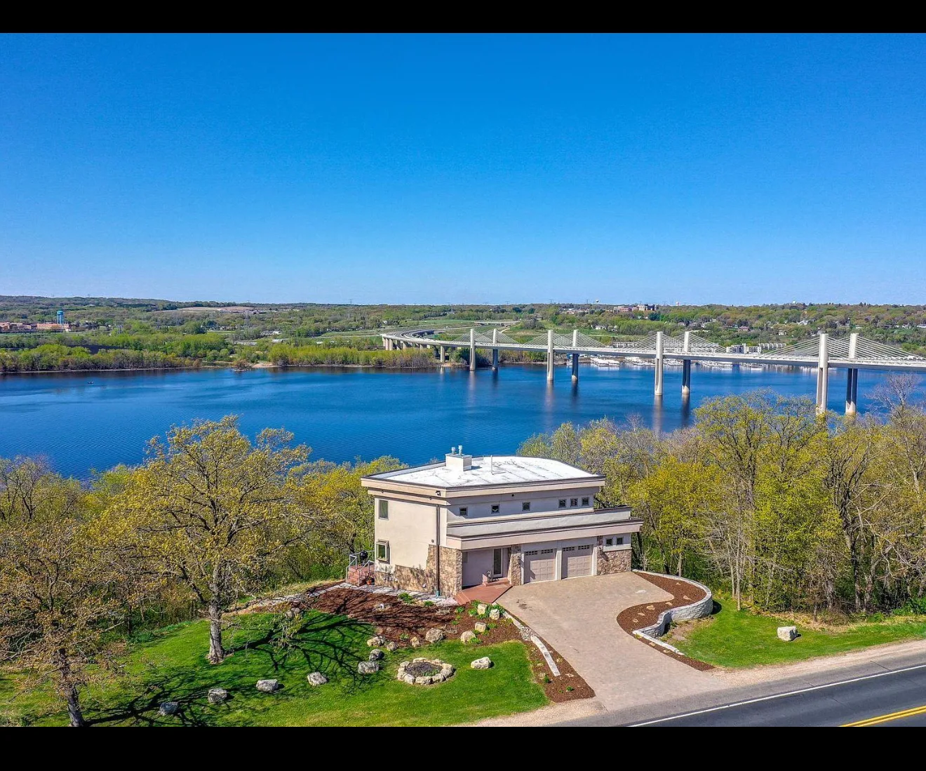 Modern house on a hillside overlooking a wide river with a bridge in the background