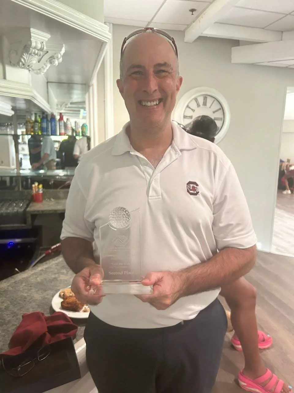 Man holding a second place trophy at the FORE the KIDS Golf Tournament awards ceremony