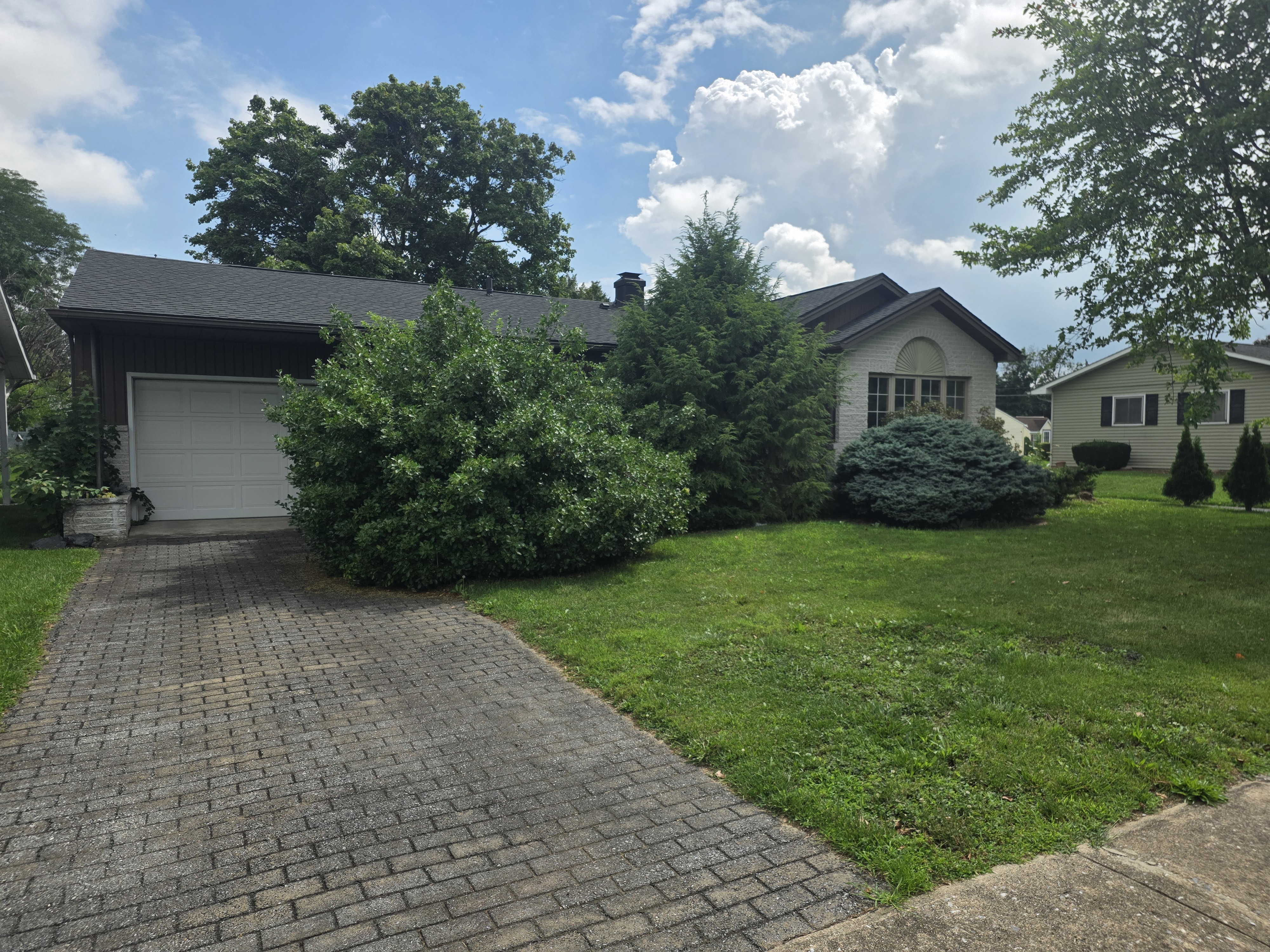 Front exterior of 117 S 9th St, a ranch-style twin home with brick and siding facade, landscaped yard, and attached garage