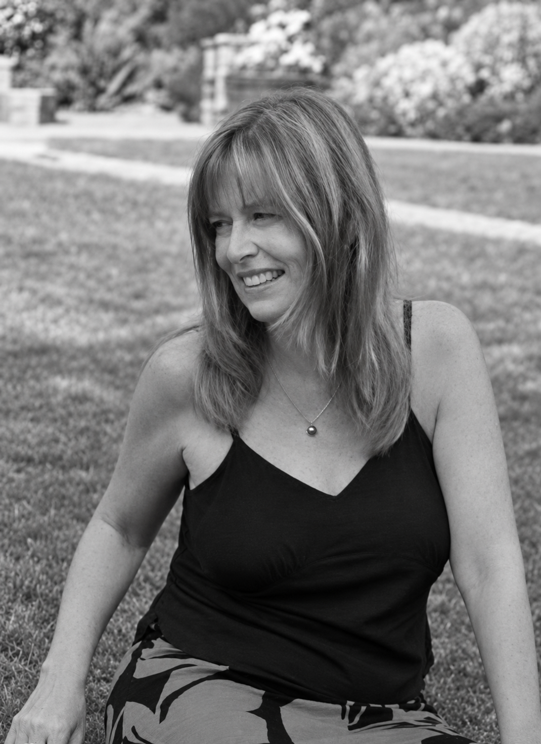 Carol seated in a garden at Chalice Well, photographed in black and white.