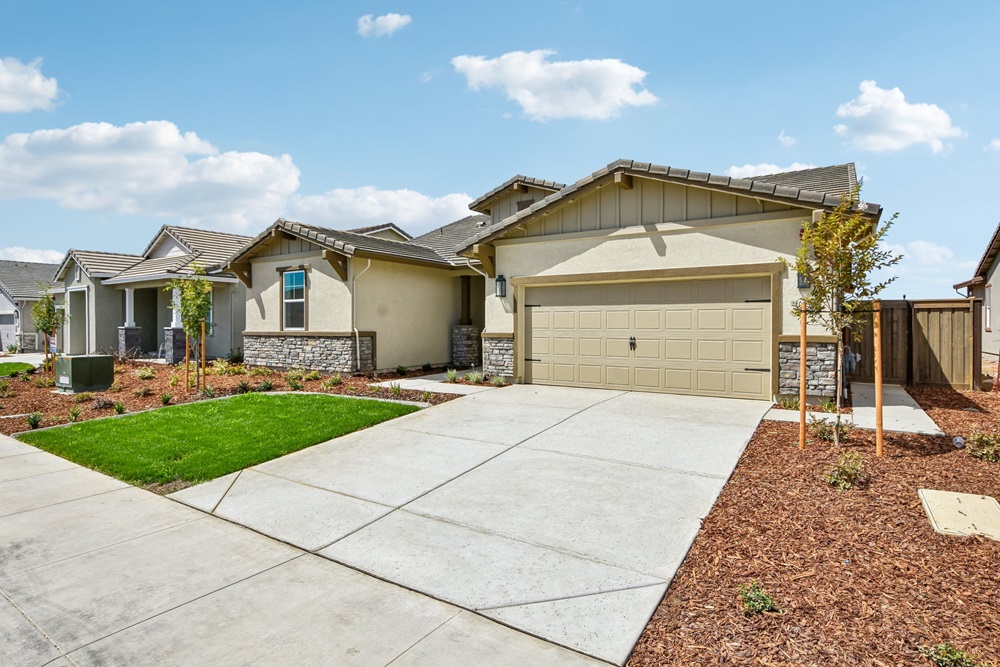 The front exterior of the single-story tan-stucco home at 10252 Kanok Way in Esplanade at Madeira Ranch, with stone accents and a two-car garage