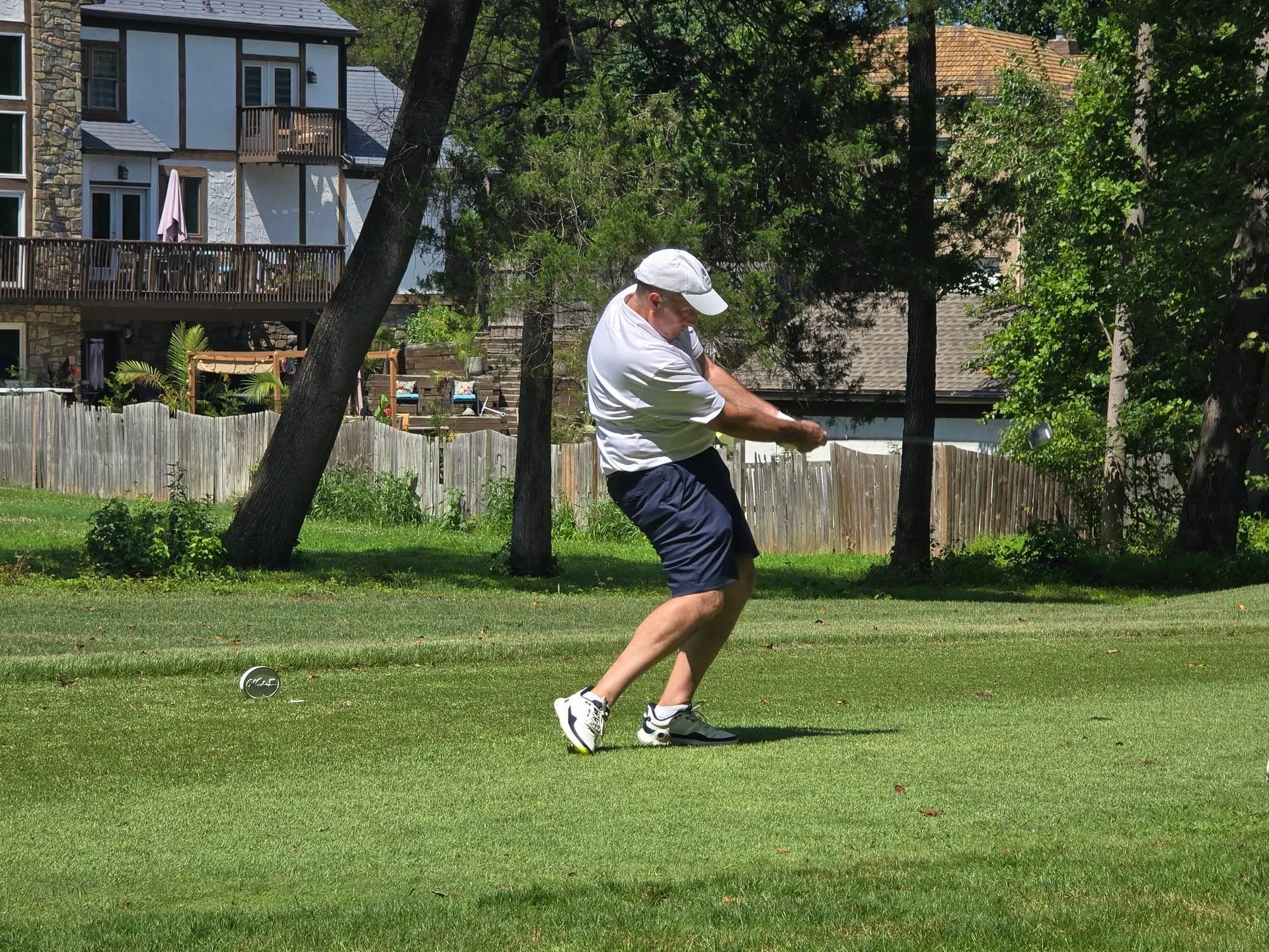 Man mid-swing on the tee box at the FORE the KIDS Golf Tournament