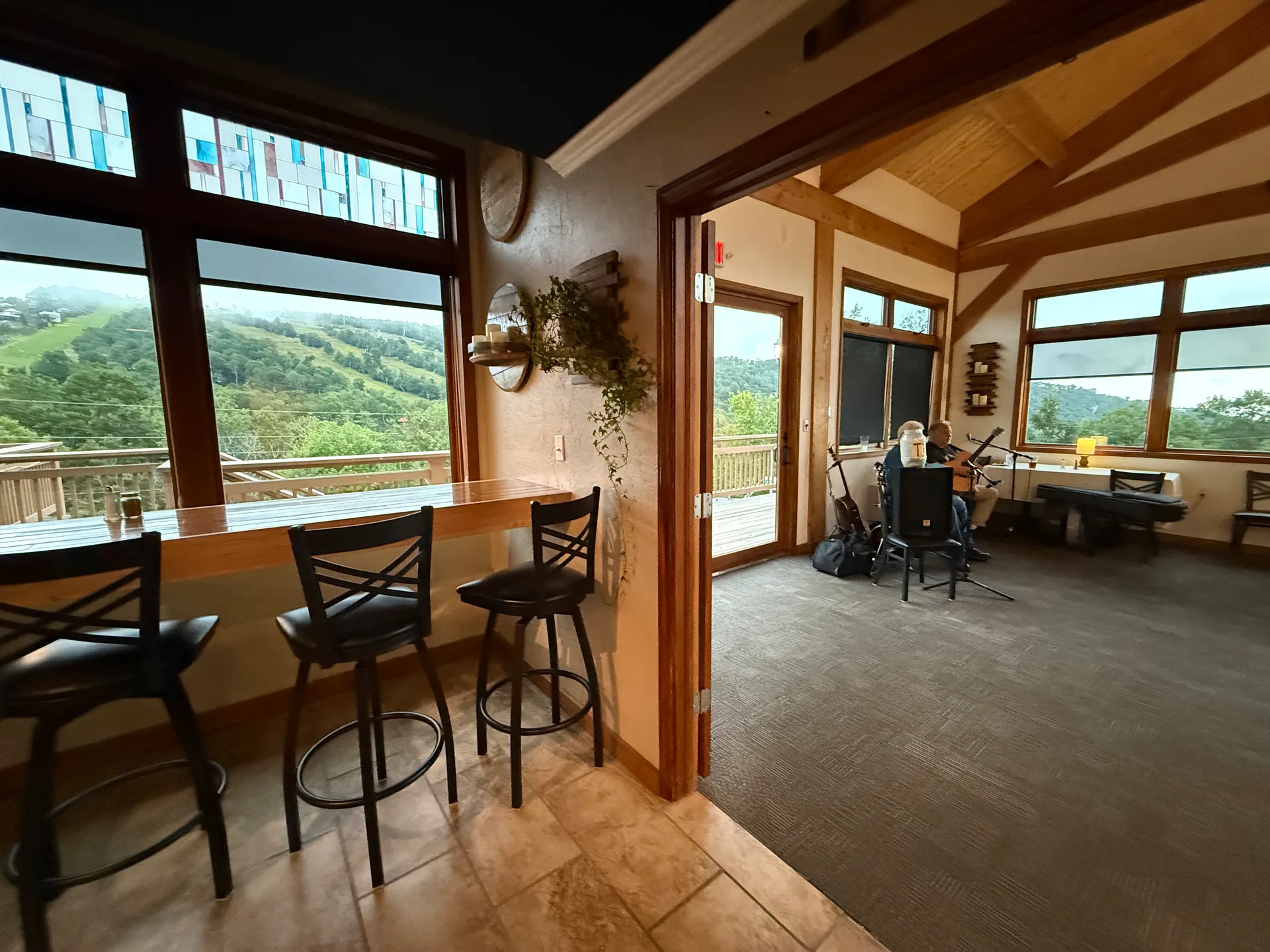 Bar-height seating with scenic mountain views through large windows at the Steakhouse at Alpen Inn, with live music in the adjoining room