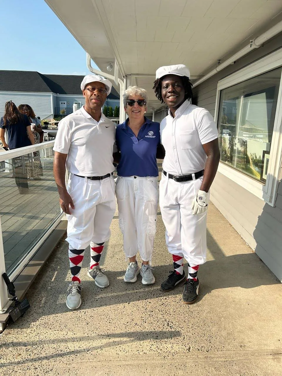 Golfers in classic knickerbocker-style attire pose with a Boys & Girls Clubs representative