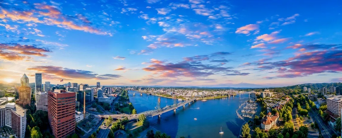 Sunset cityscape of the Pacific Northwest with a river, bridge, and skyline