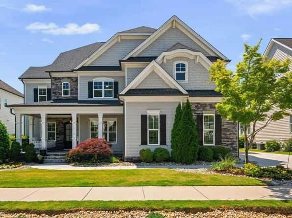 Modern-traditional house with light-grey siding, stone masonry, and dark shutters in Carpenter Village, Cary NC