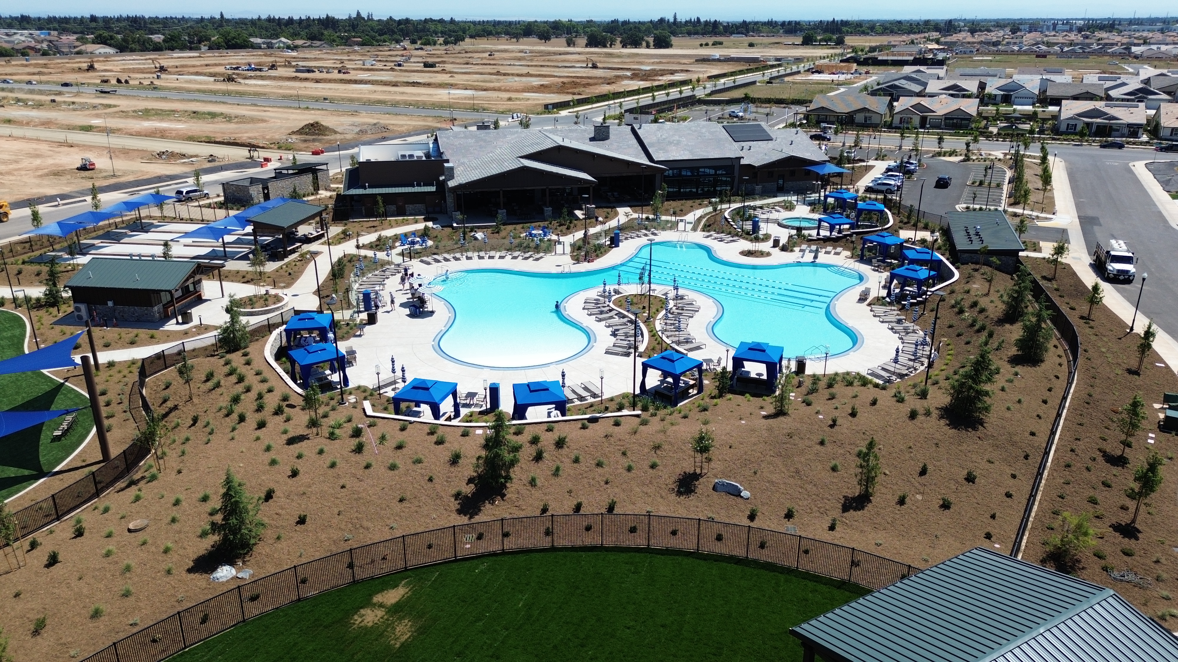 Aerial view of the completed Lodge and pool at Esplanade at Madeira Ranch in Elk Grove, with the community still building out around them
